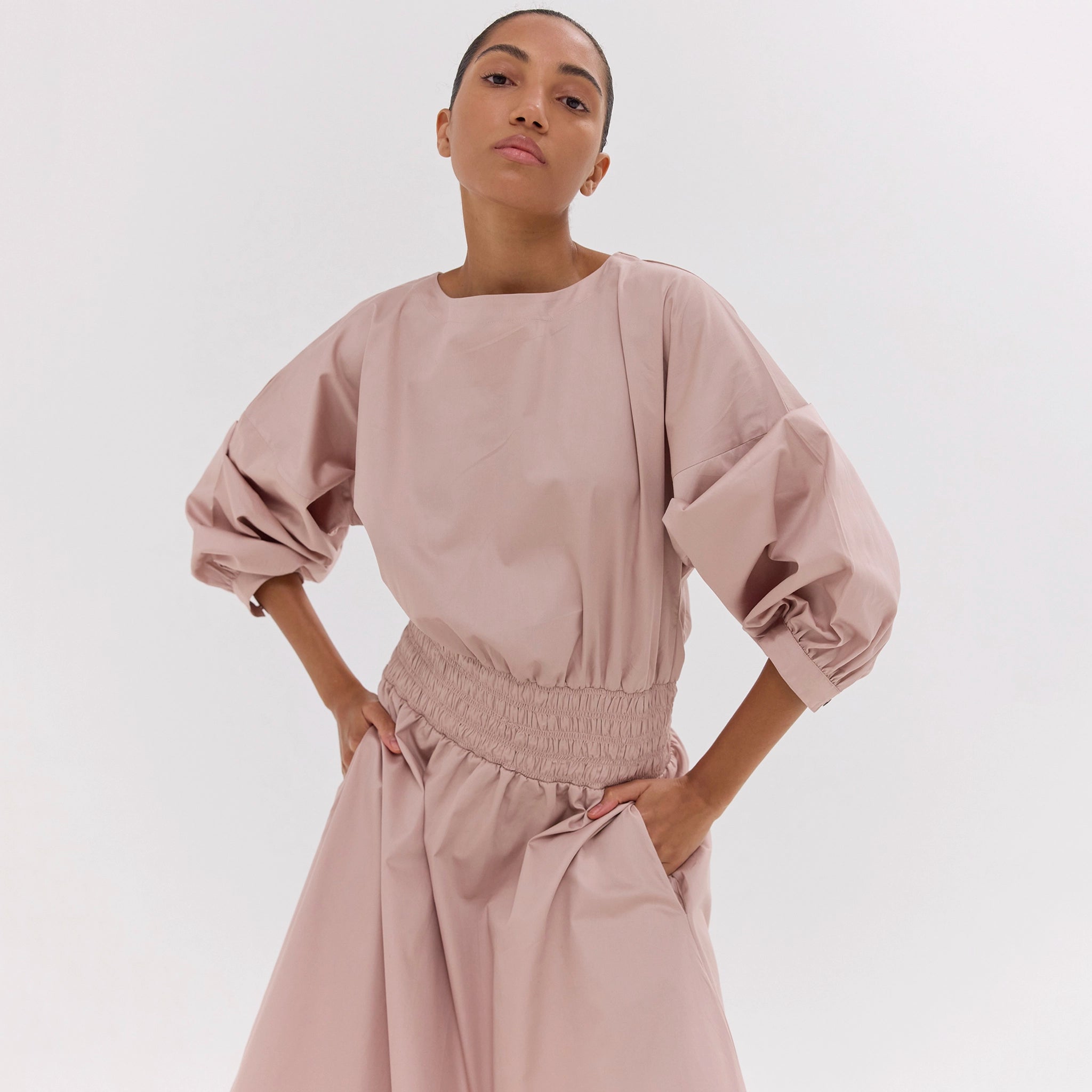 Woman wearing a pink outfit with puffed sleeves on a white background