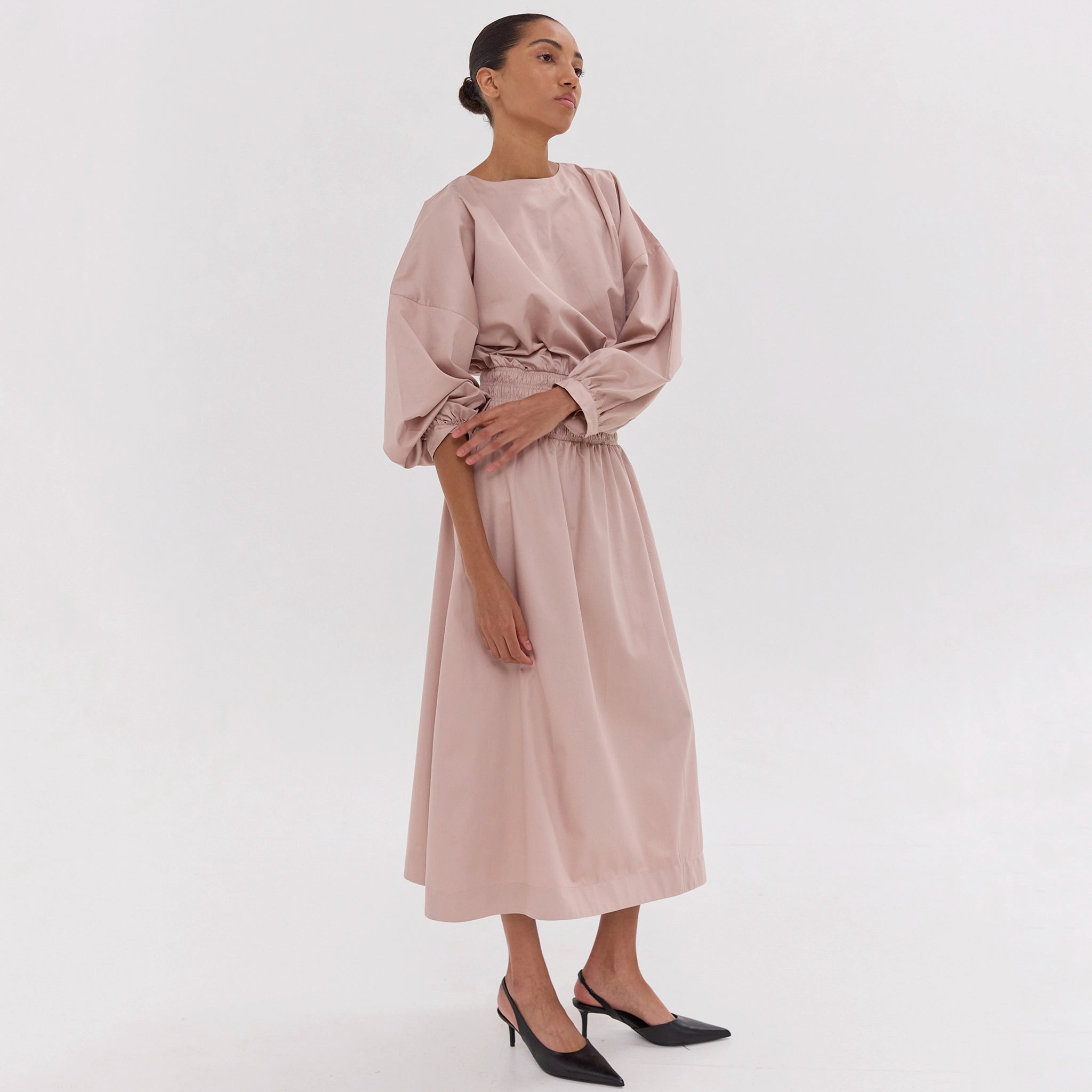 Woman wearing a light pink dress on a white background