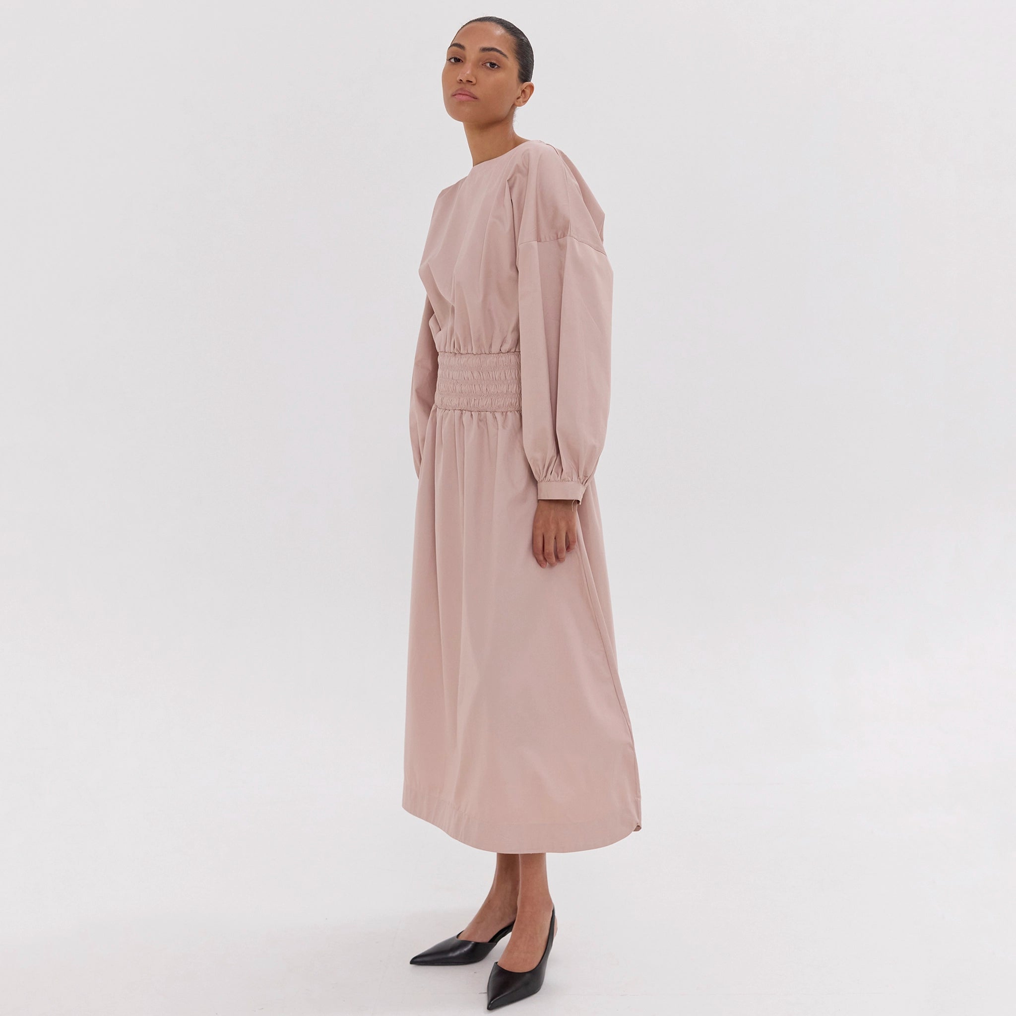 Woman wearing a long beige dress on a white background