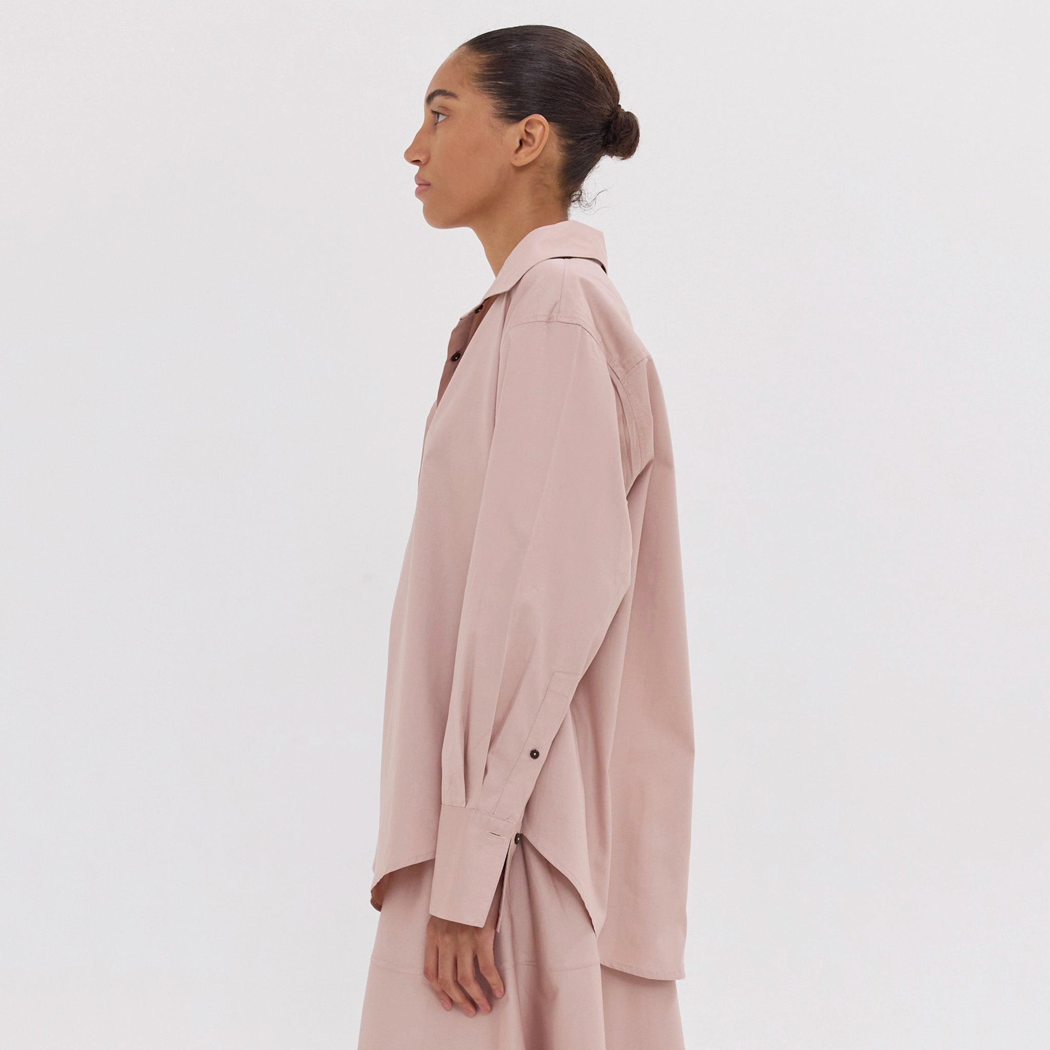 Woman wearing a light pink trench coat on a white background