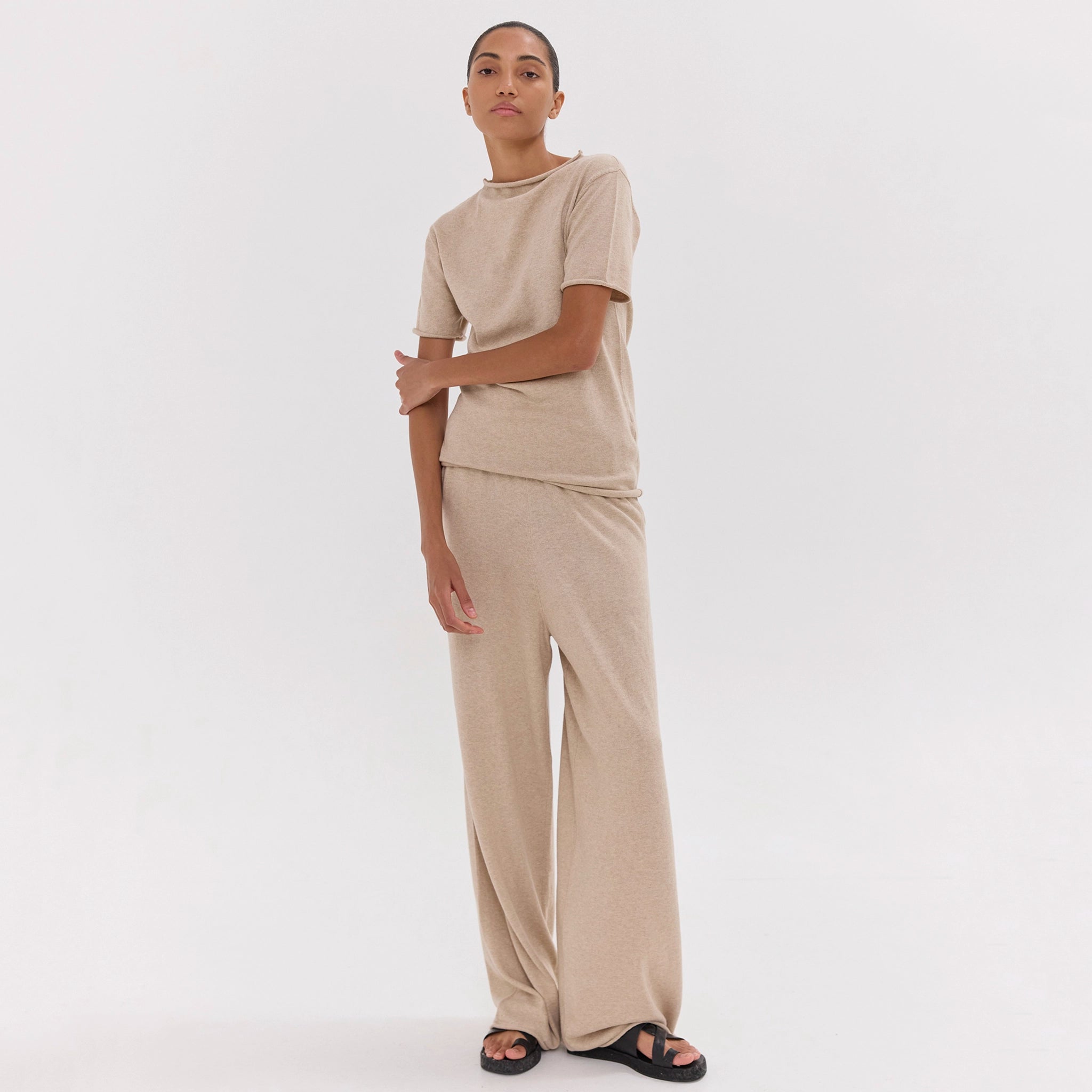 Person wearing a beige outfit on a white background
