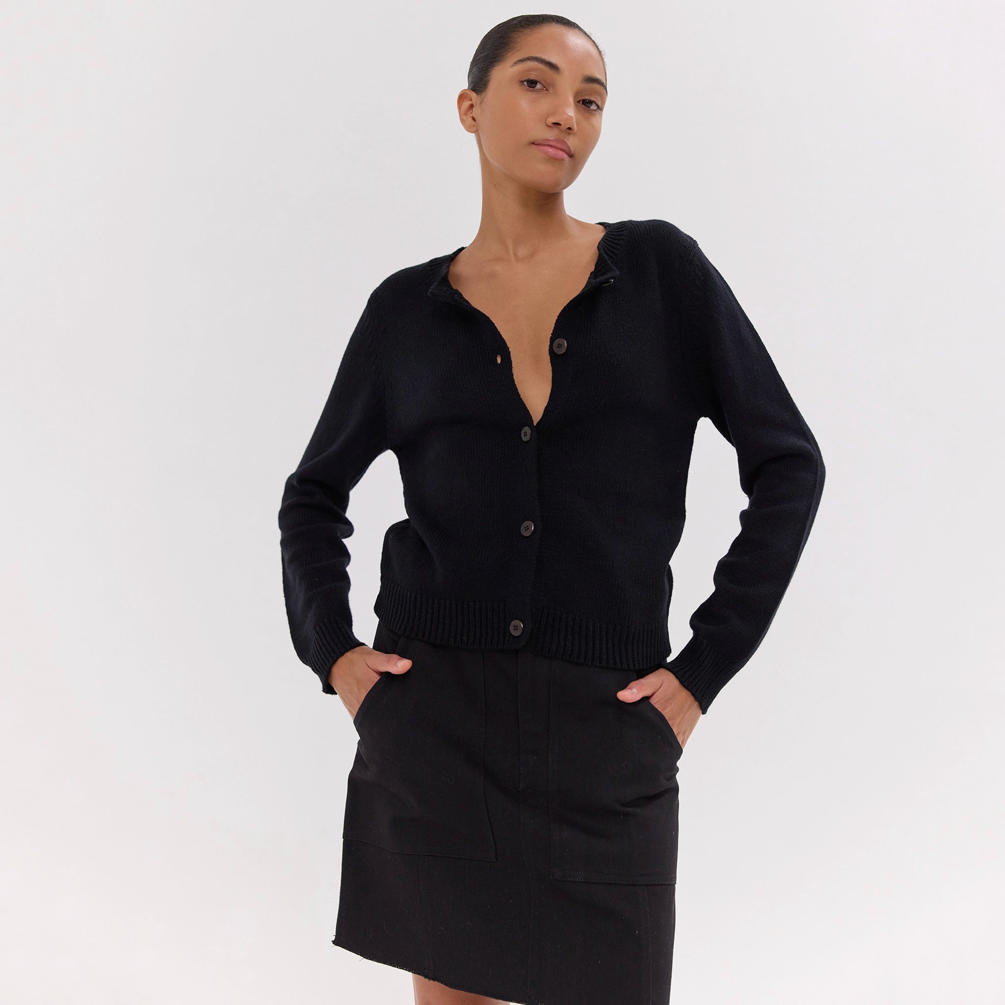 Woman wearing a black cardigan and skirt on a white background