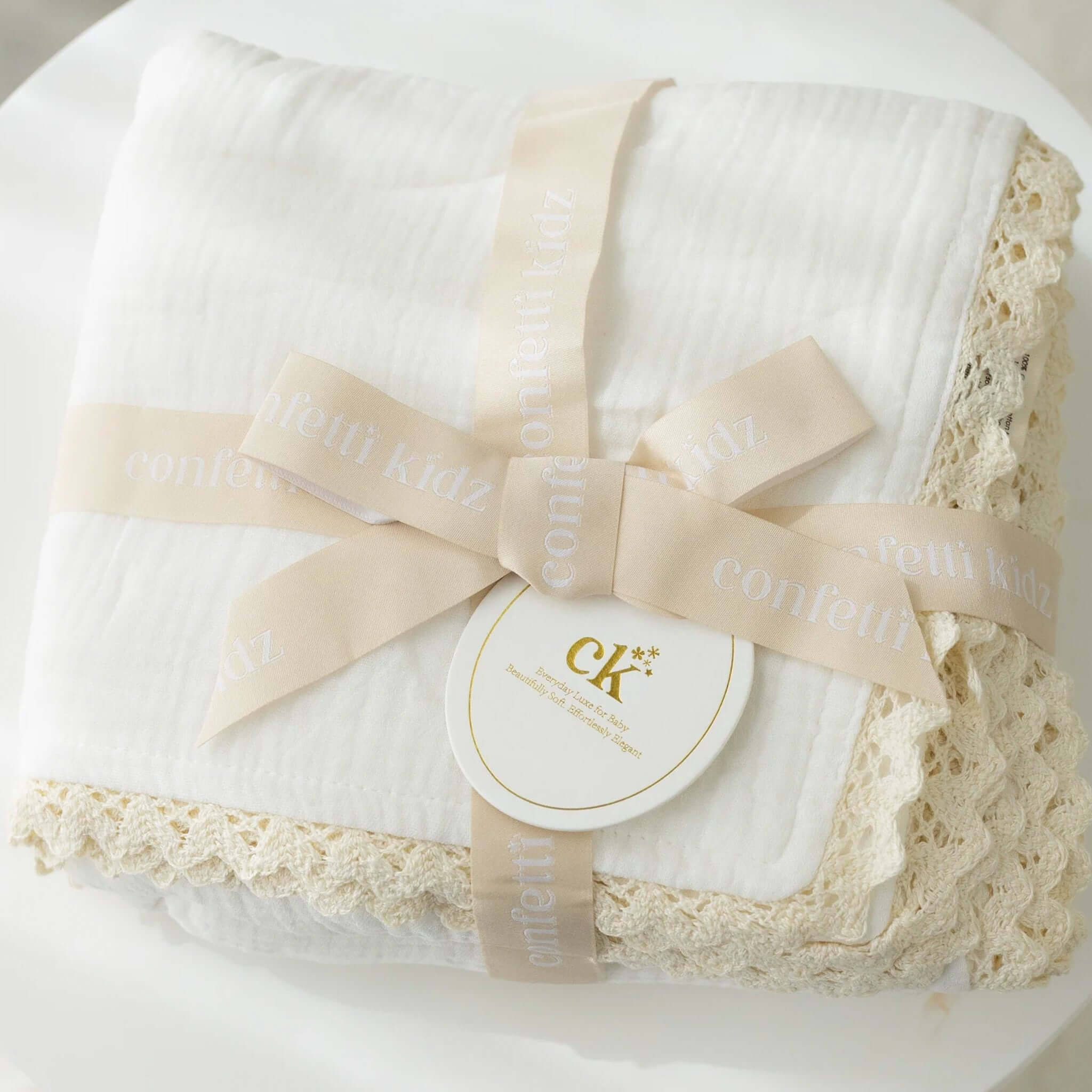 Confetti Kidz Classic Muslin Blanket - White wrapped in a decorative ribbon with lace trim.