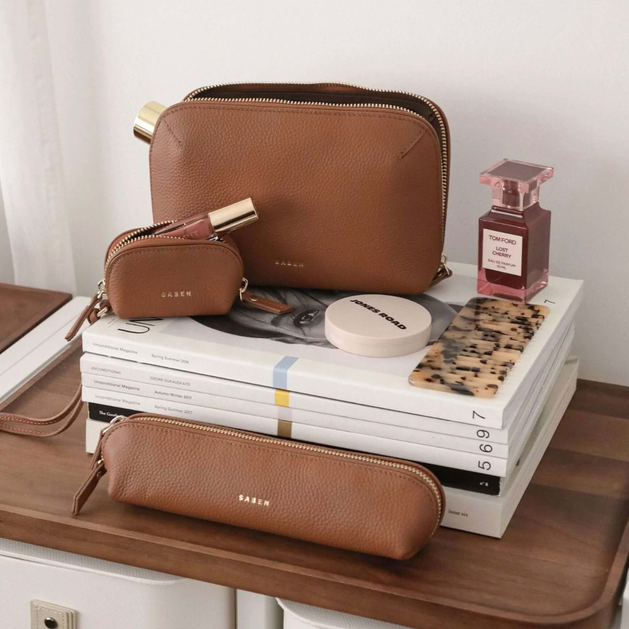 Saben Tate Tech / Cosmetic Pouch - Tan leather cosmetic pouch and accessories on vanity with makeup, perfume, and comb