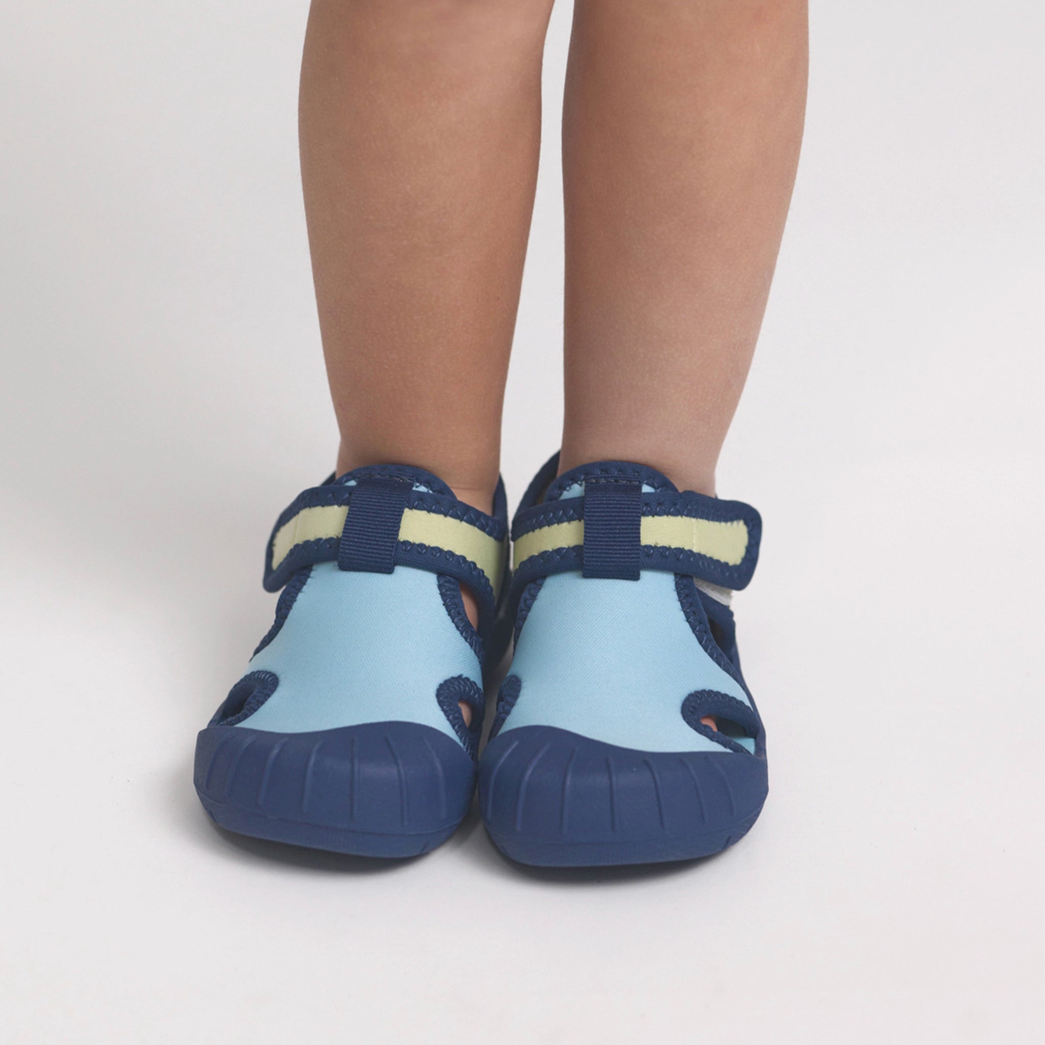 Children's blue and navy shoes with yellow accents on a light gray background