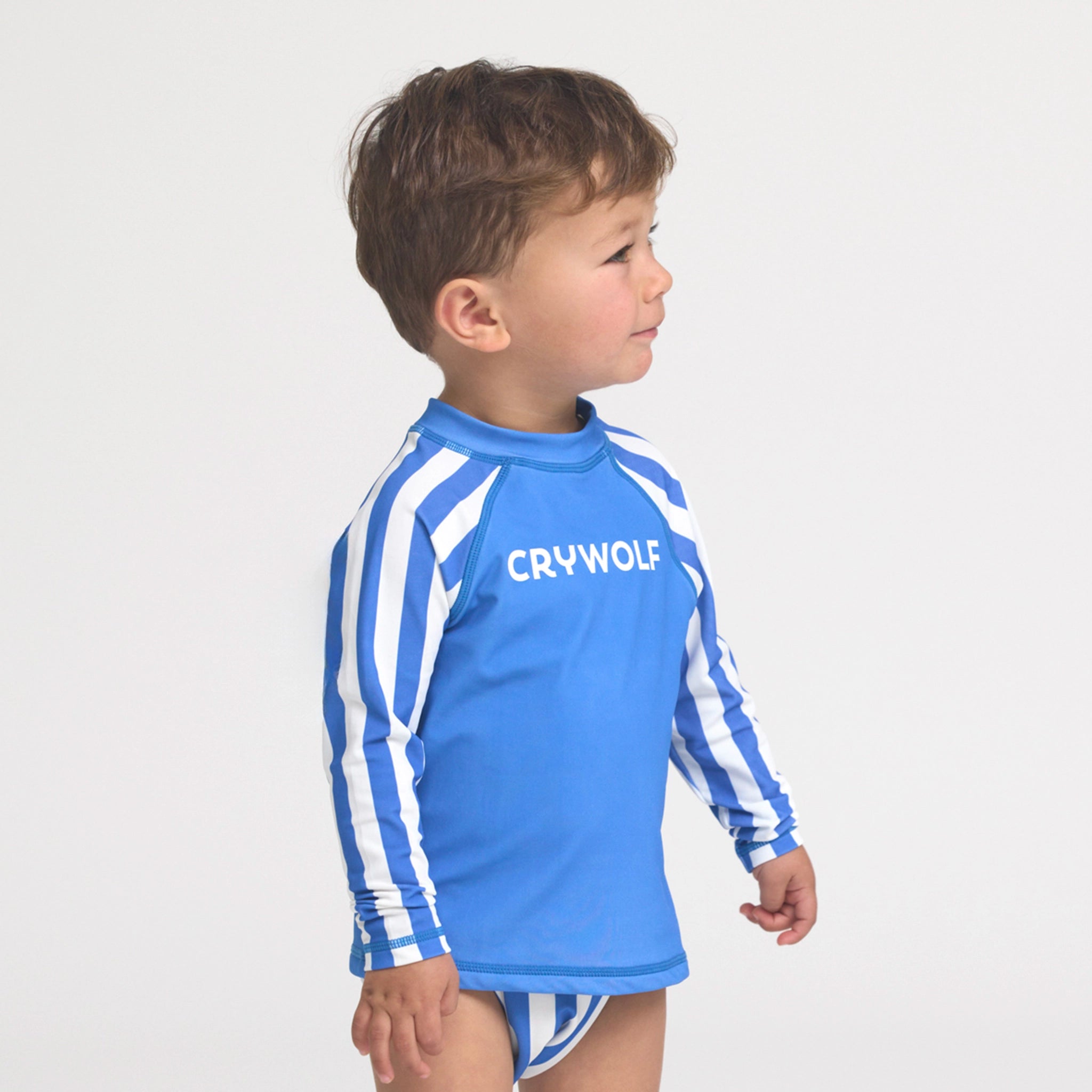Boy wearing a blue and white striped rash vest on a white background