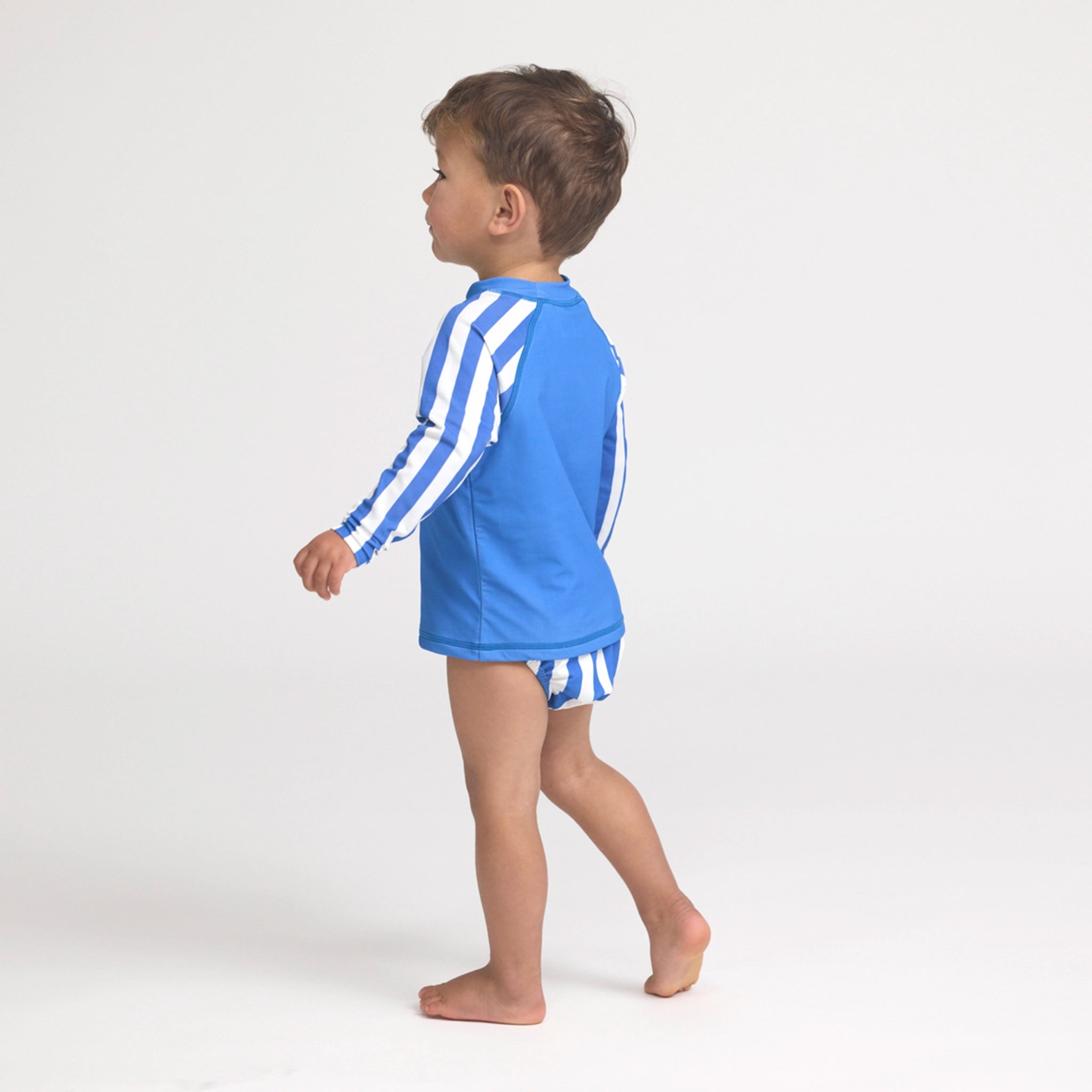 Boy wearing a blue and white striped rash vest on a white background