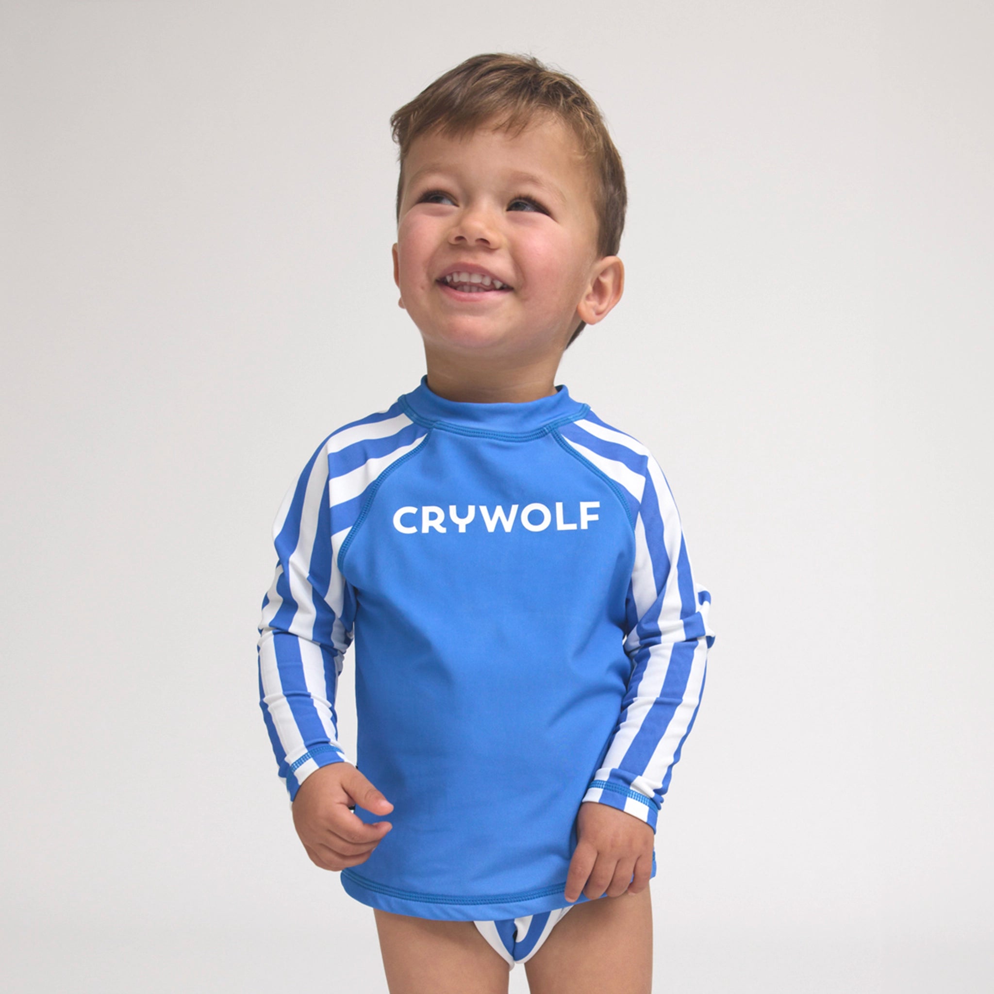 Boy wearing a blue and white striped rash vest on a white background