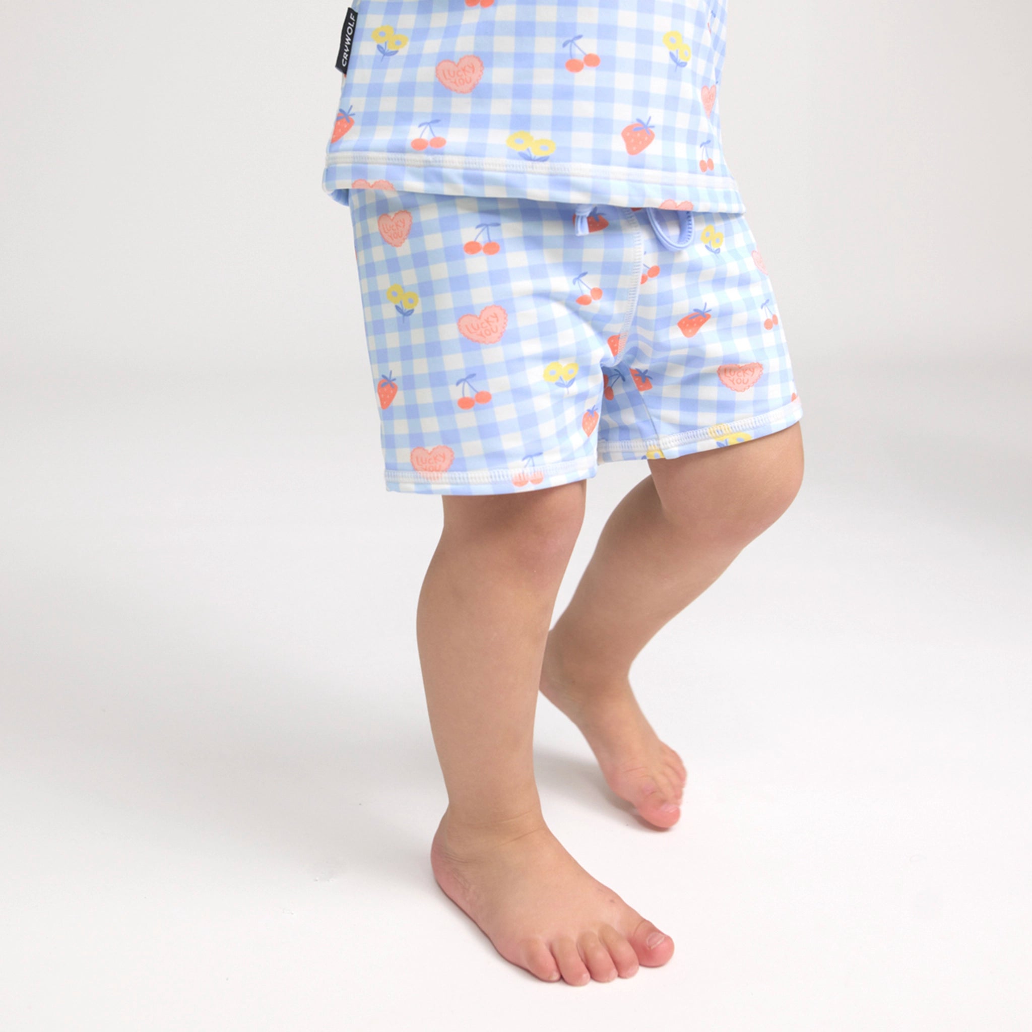Toddler wearing patterned baby swim shorts on white background
