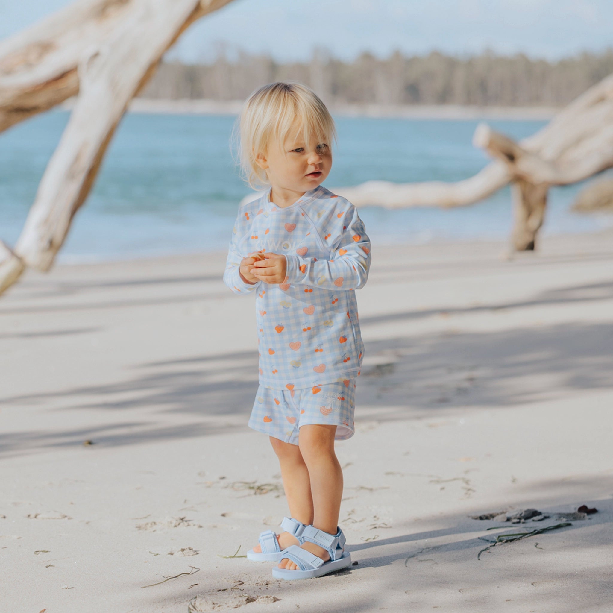 Toddler wearing patterned baby swim shorts on a beach