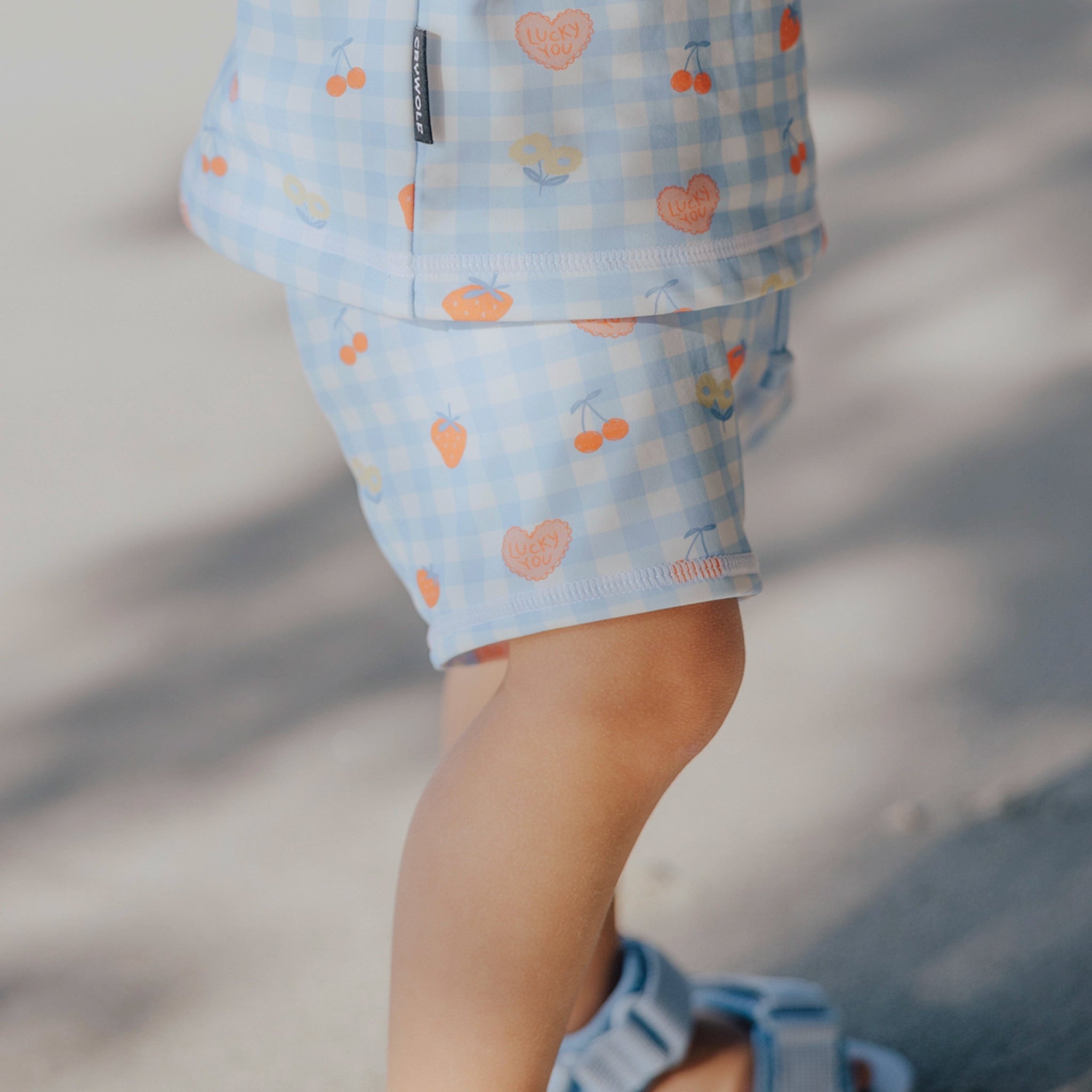 Toddler wearing patterned baby swim shorts on a beach