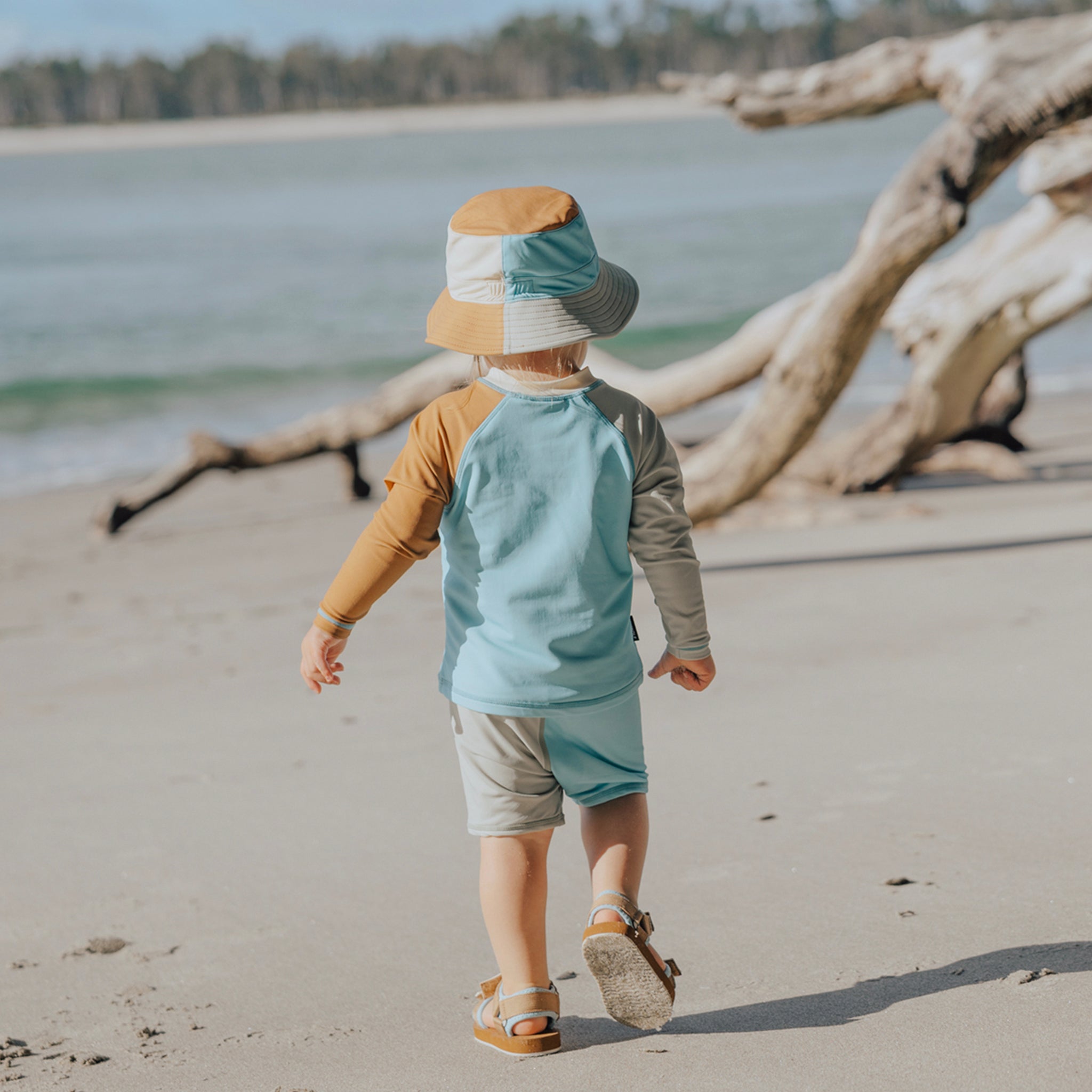 Toddler wearing geometric baby swim shorts on a beach