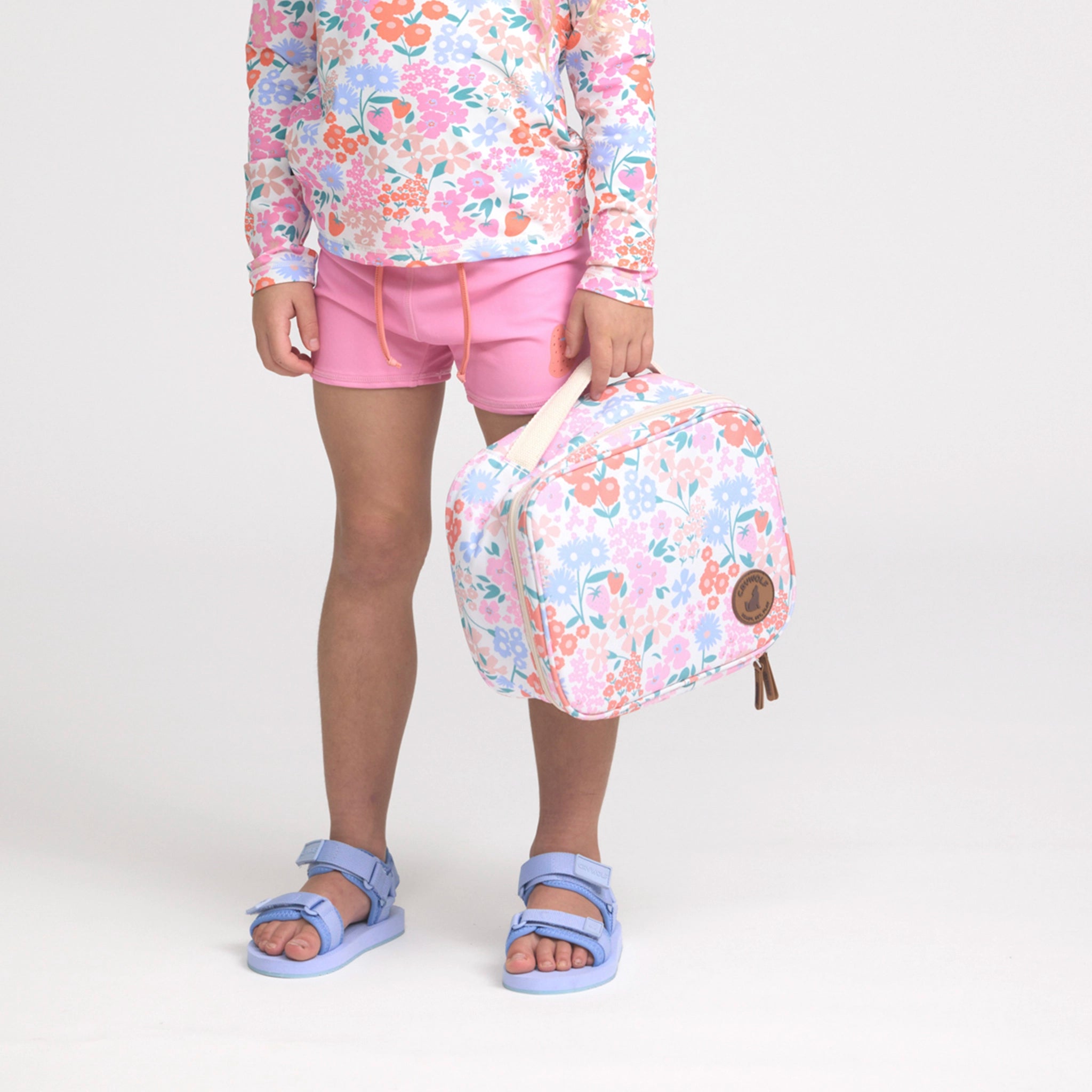 Person wearing a floral outfit with a matching floral bag on a white background