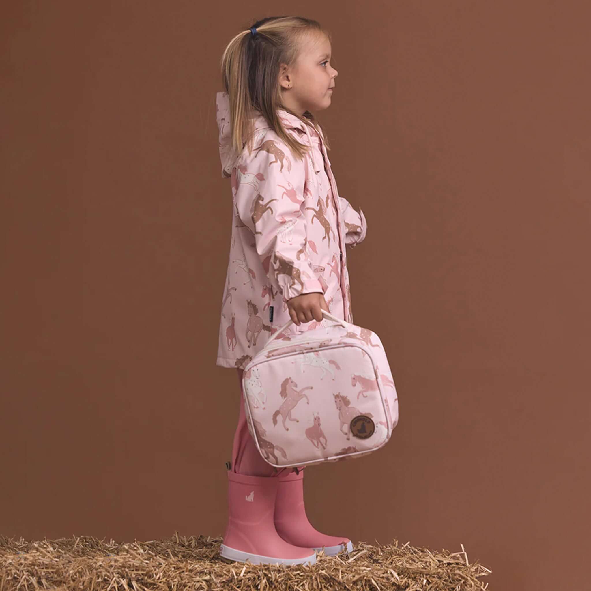 Alt Tag: Crywolf Everyday Lunch Bag - Blush Ponies insulated kids lunch bag in blush ponies print, carried by child outdoors