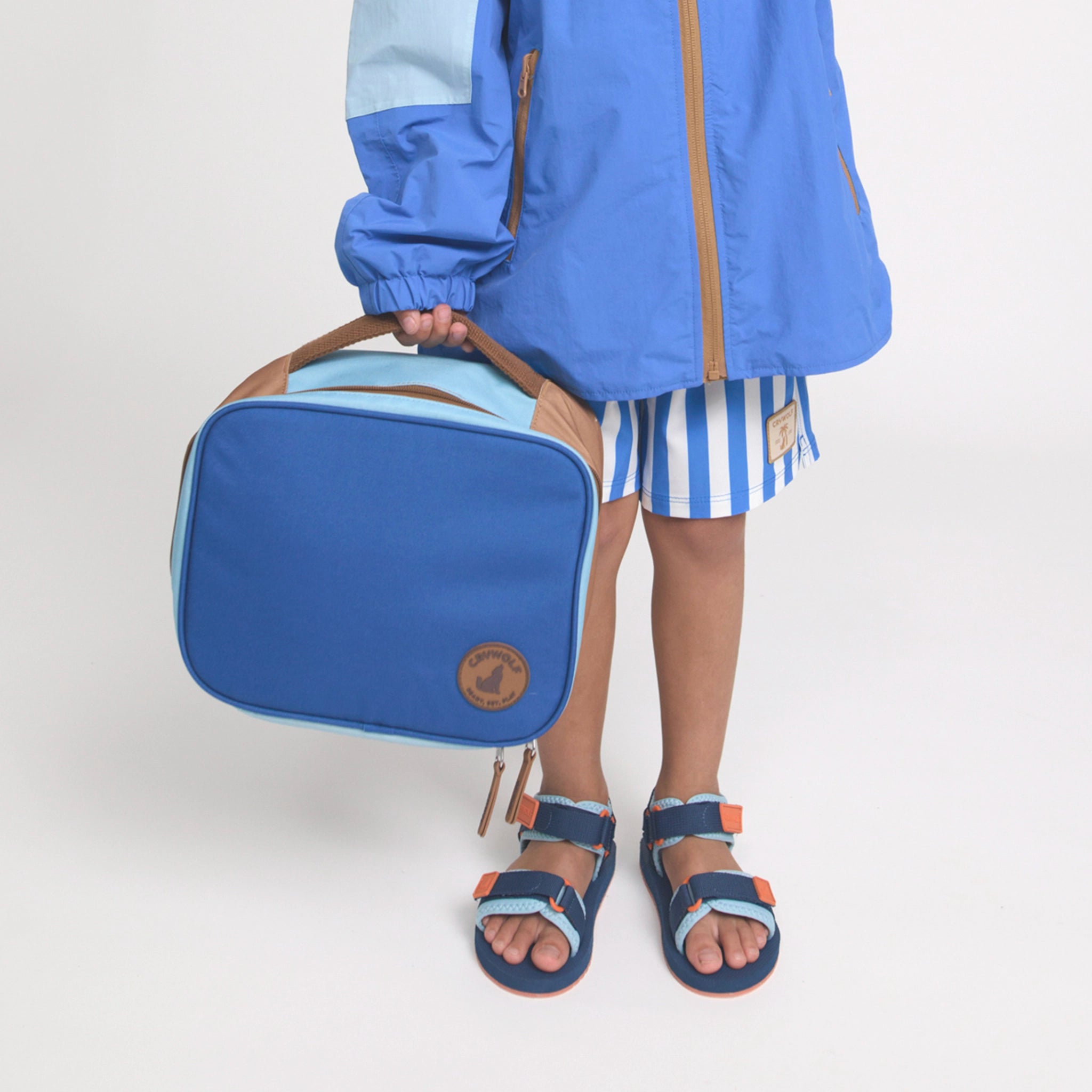 Child holding a blue and beige bag against a white background