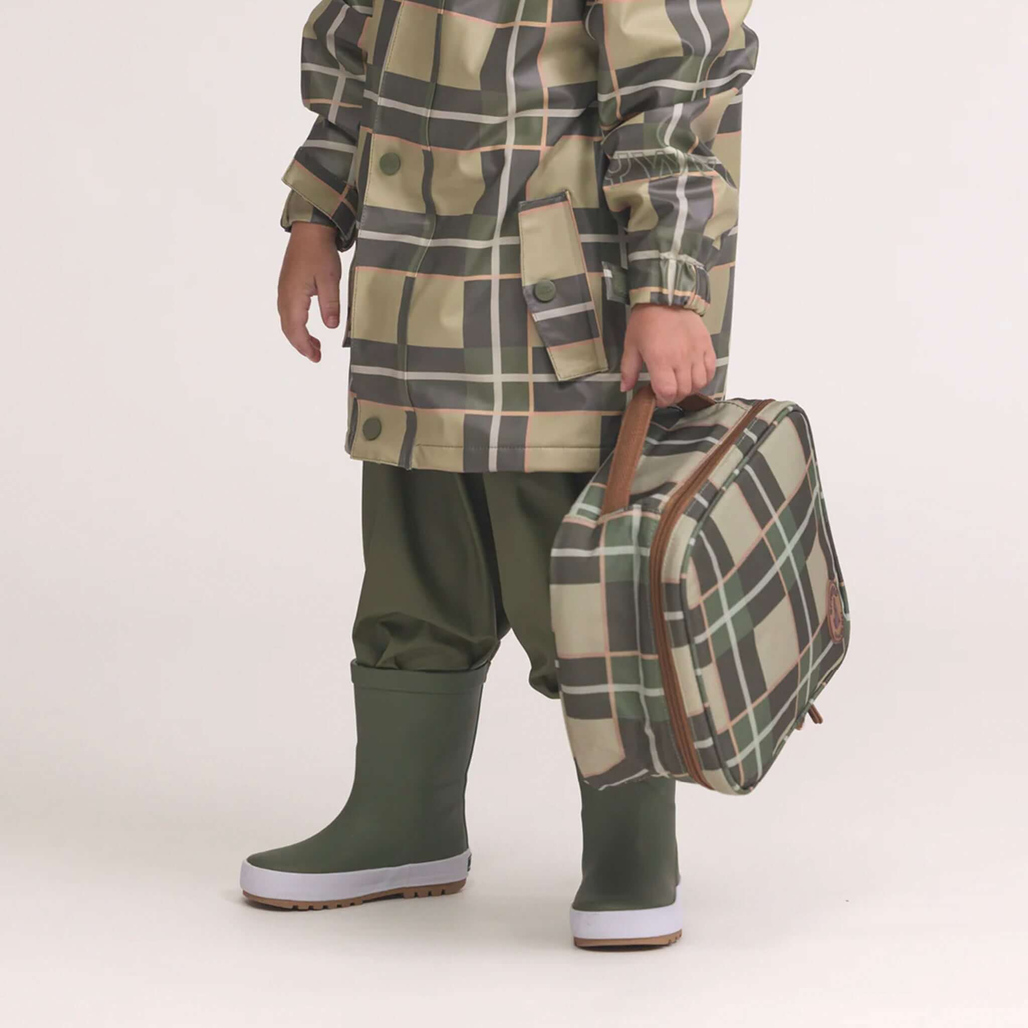 Alt Tag: Crywolf Everyday Lunch Bag - Field Plaid insulated lunch bag in field plaid print with carry handle, held by child in rain gear
