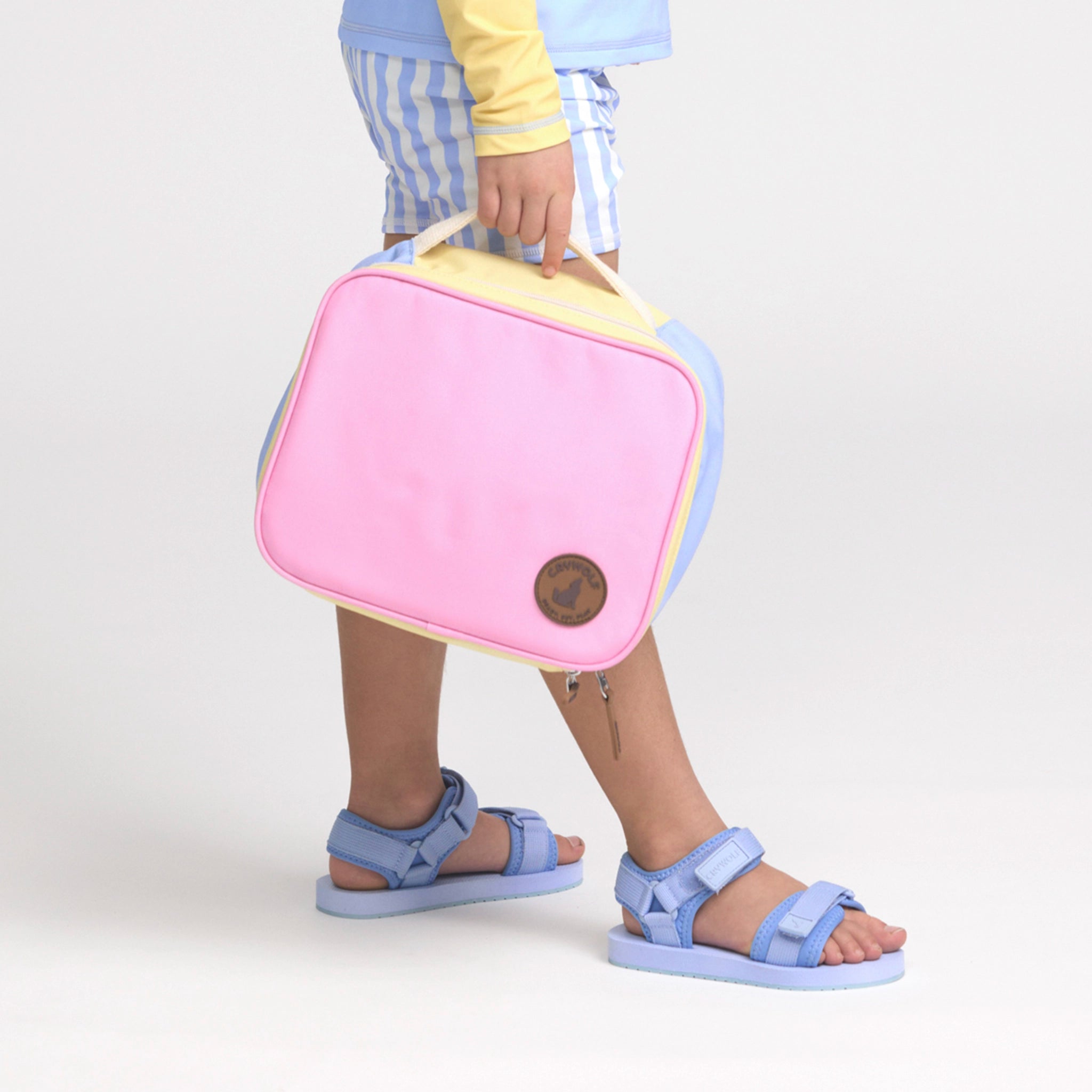 Person holding a pink and yellow bag with blue sandals on a white background