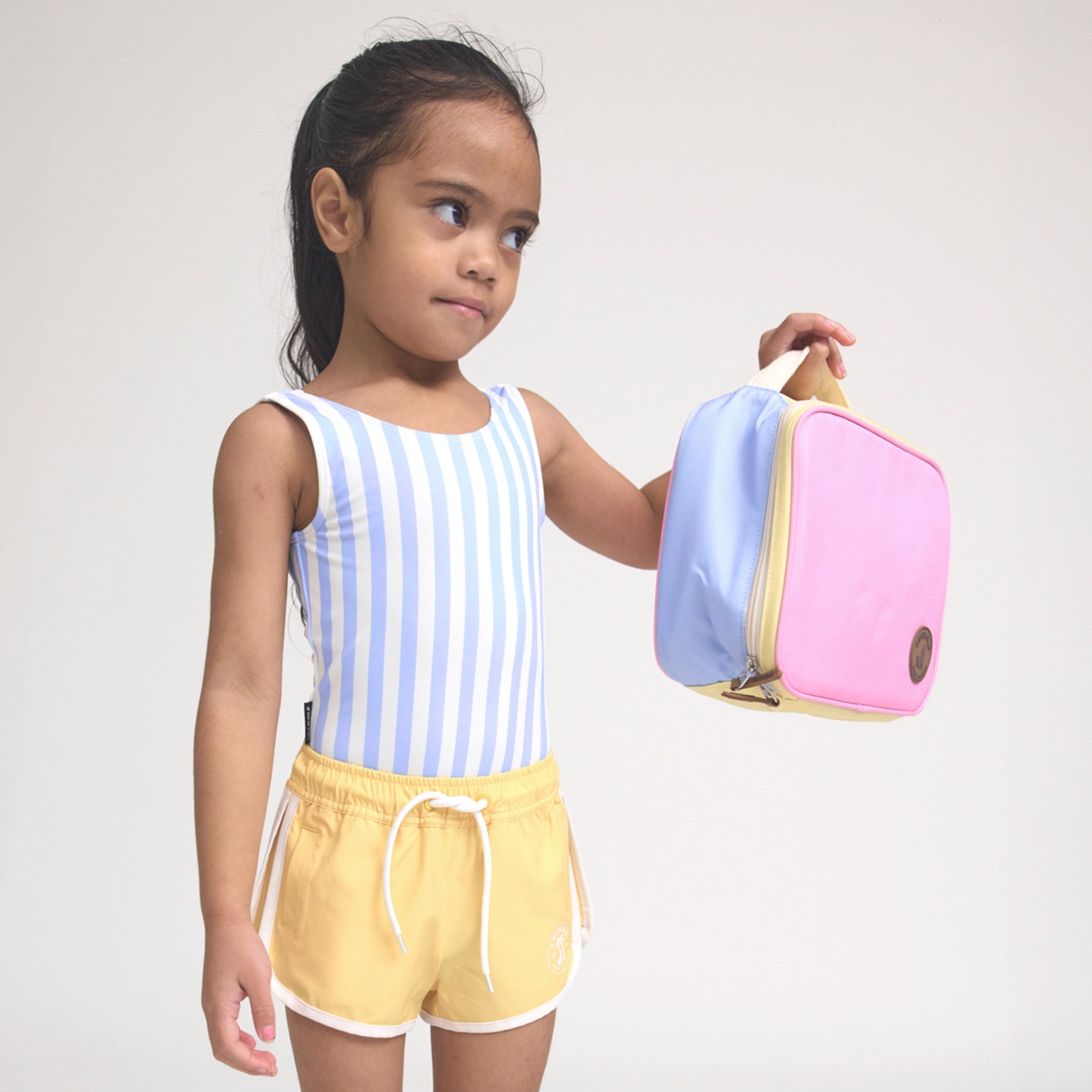 Child holding a colorful backpack against a plain background