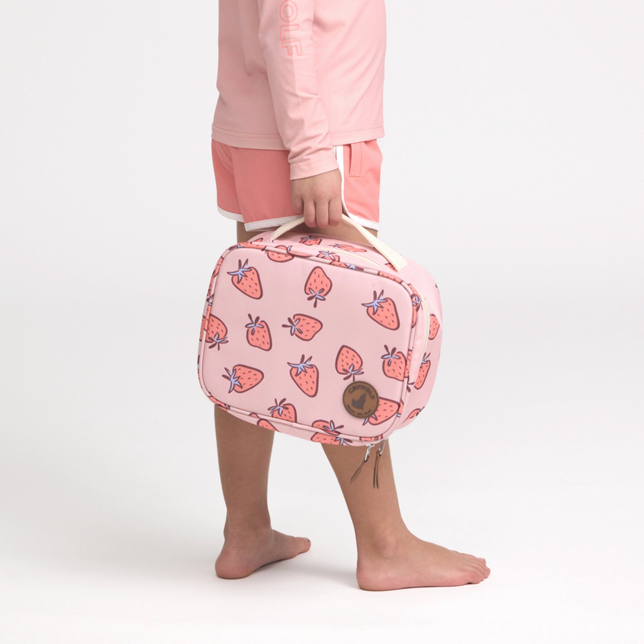 Person holding a pink lunch bag with strawberry pattern on a white background