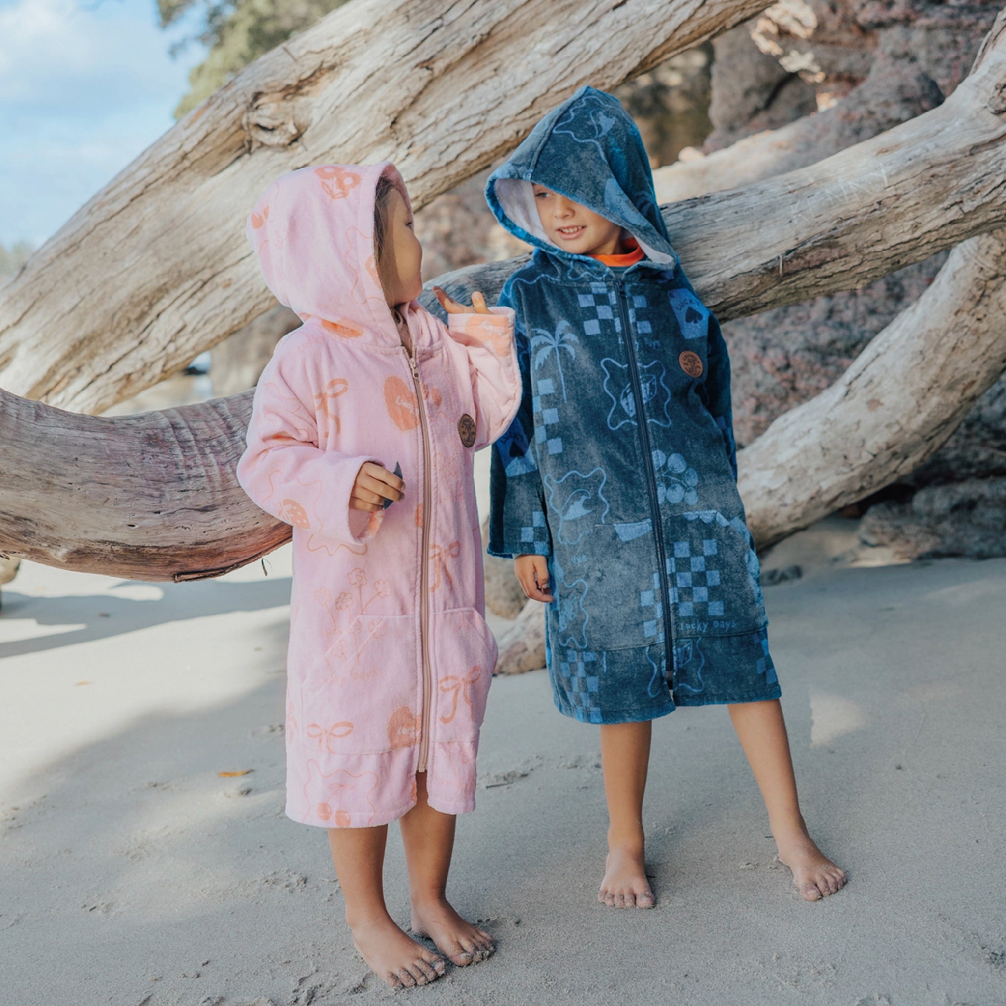 Children wearing a zip up towels at a beach