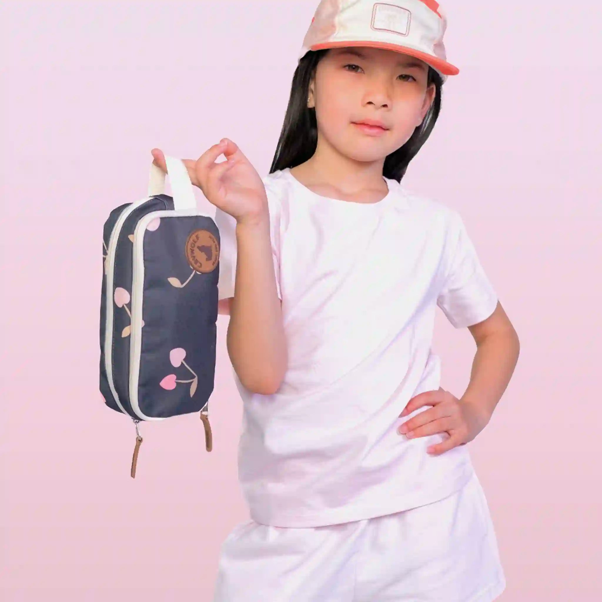 Child holding a navy blue Pencil case with cherry pattern and brand logo