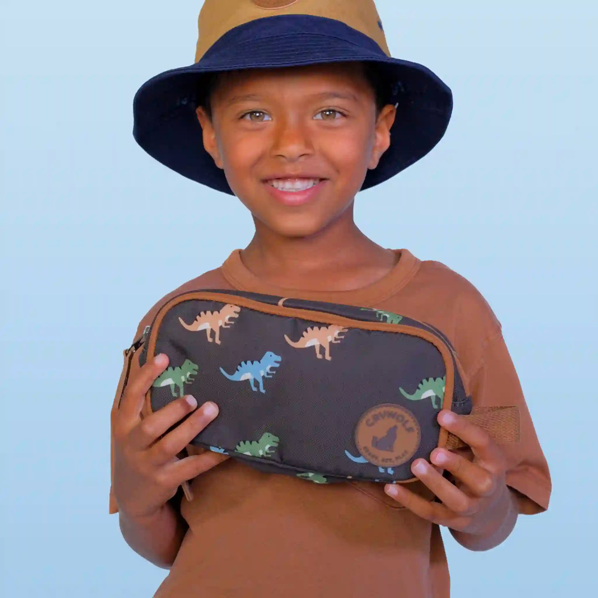 Child holding a dinosaur-patterned pencil case against a light blue background