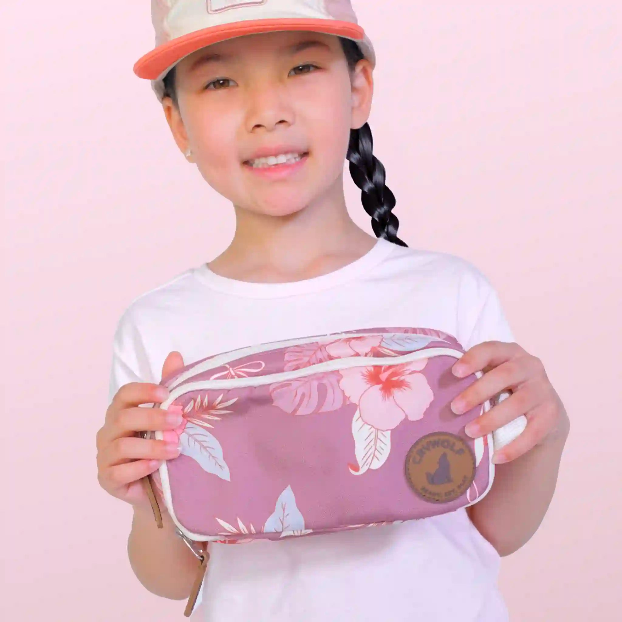 Child holding a pink floral pencil case against a light pink background