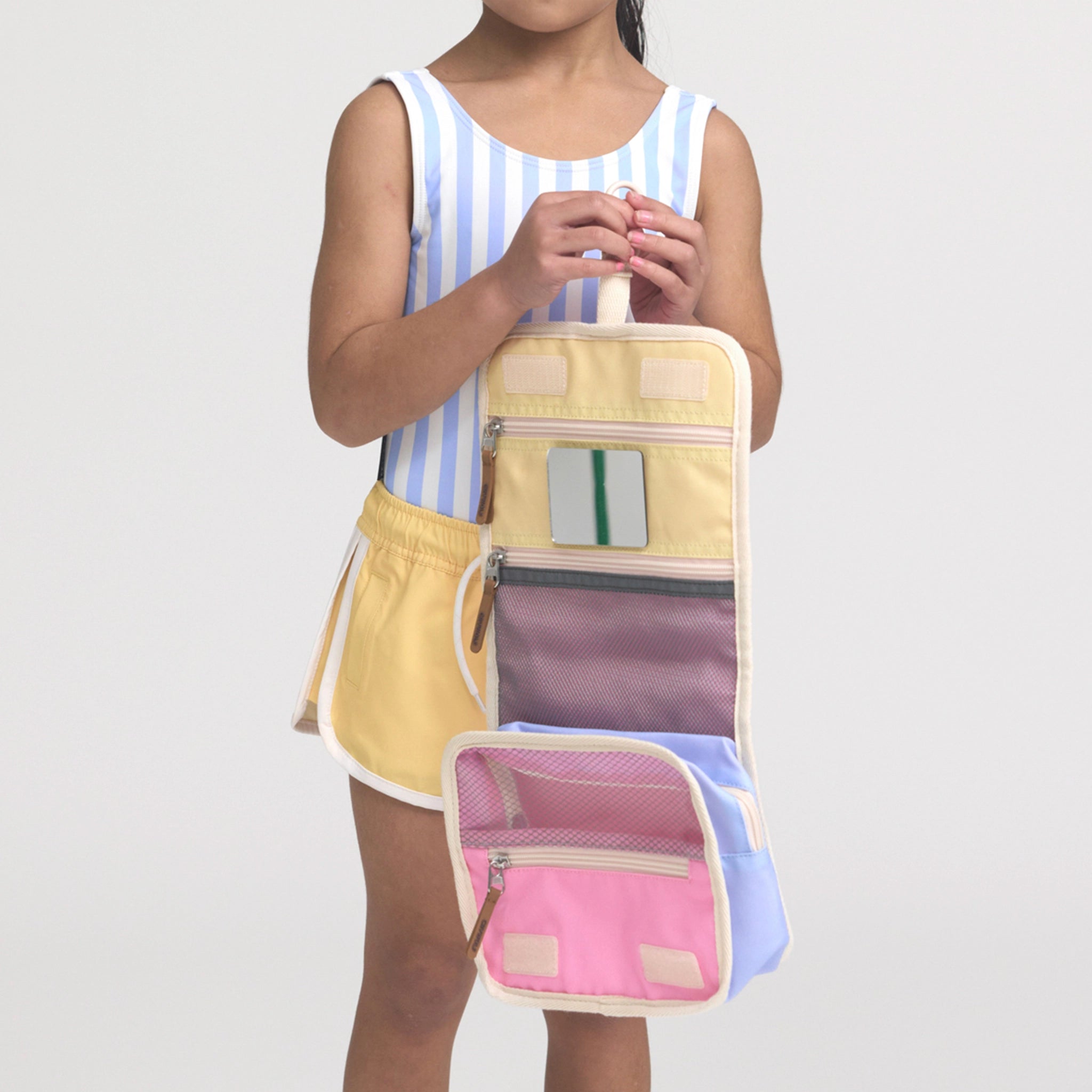 Person holding a colorful travel organizer bag with multiple compartments on a plain background