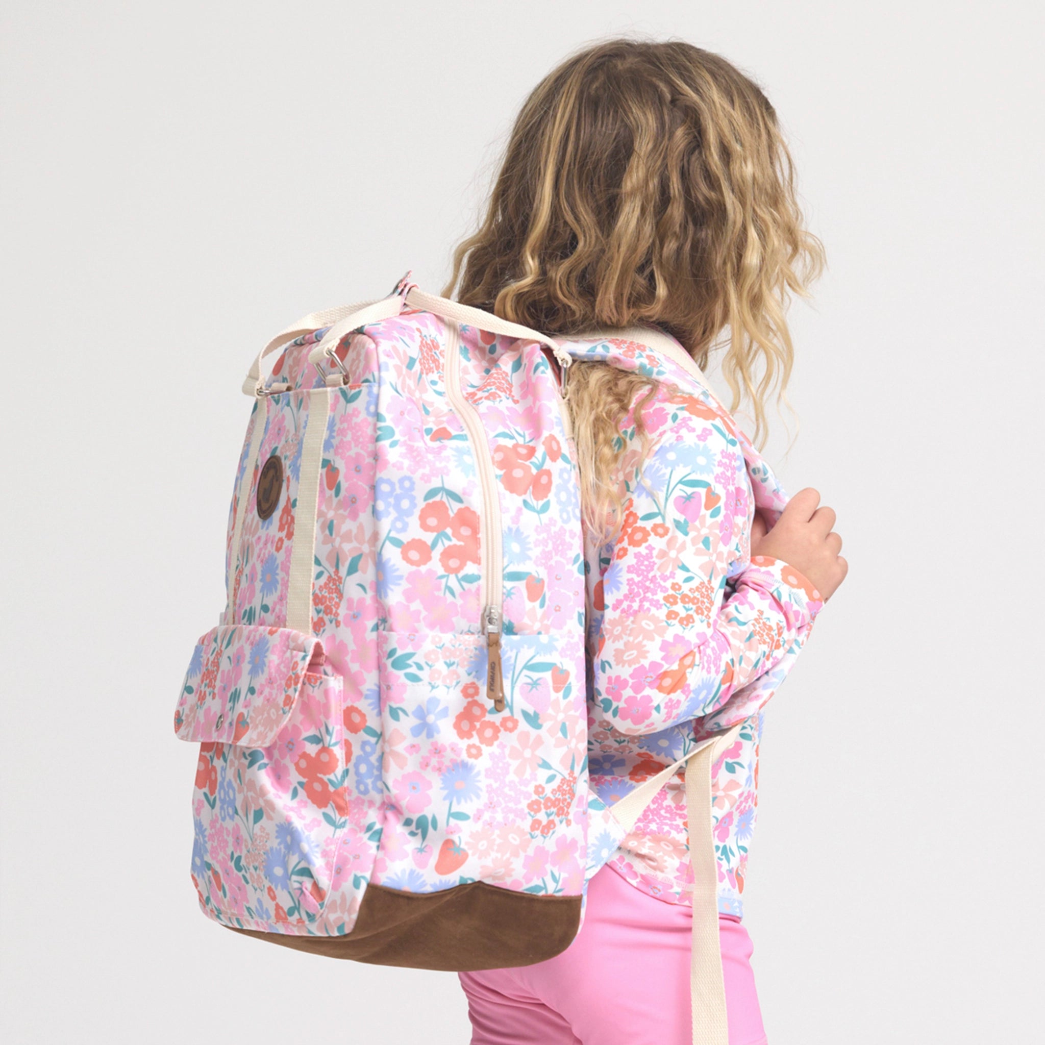 Person wearing a floral backpack on a plain background