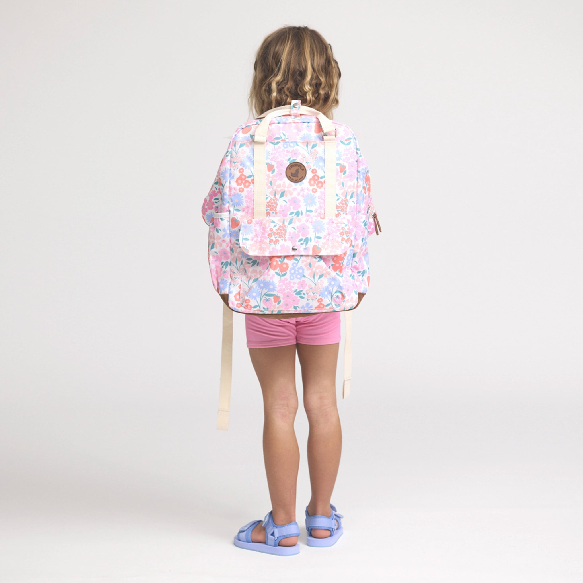 Child wearing a floral backpack on a white background