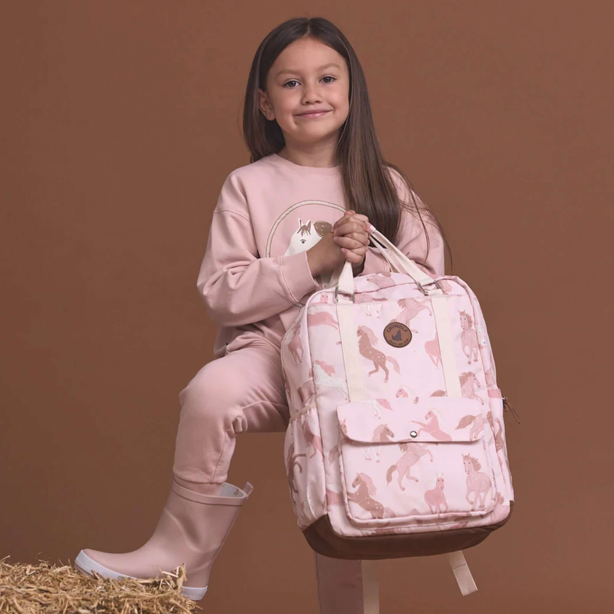 Alt Tag: Crywolf Knapsack - Blush Ponies kids water-resistant recycled backpack in blush pony print with front flap pocket