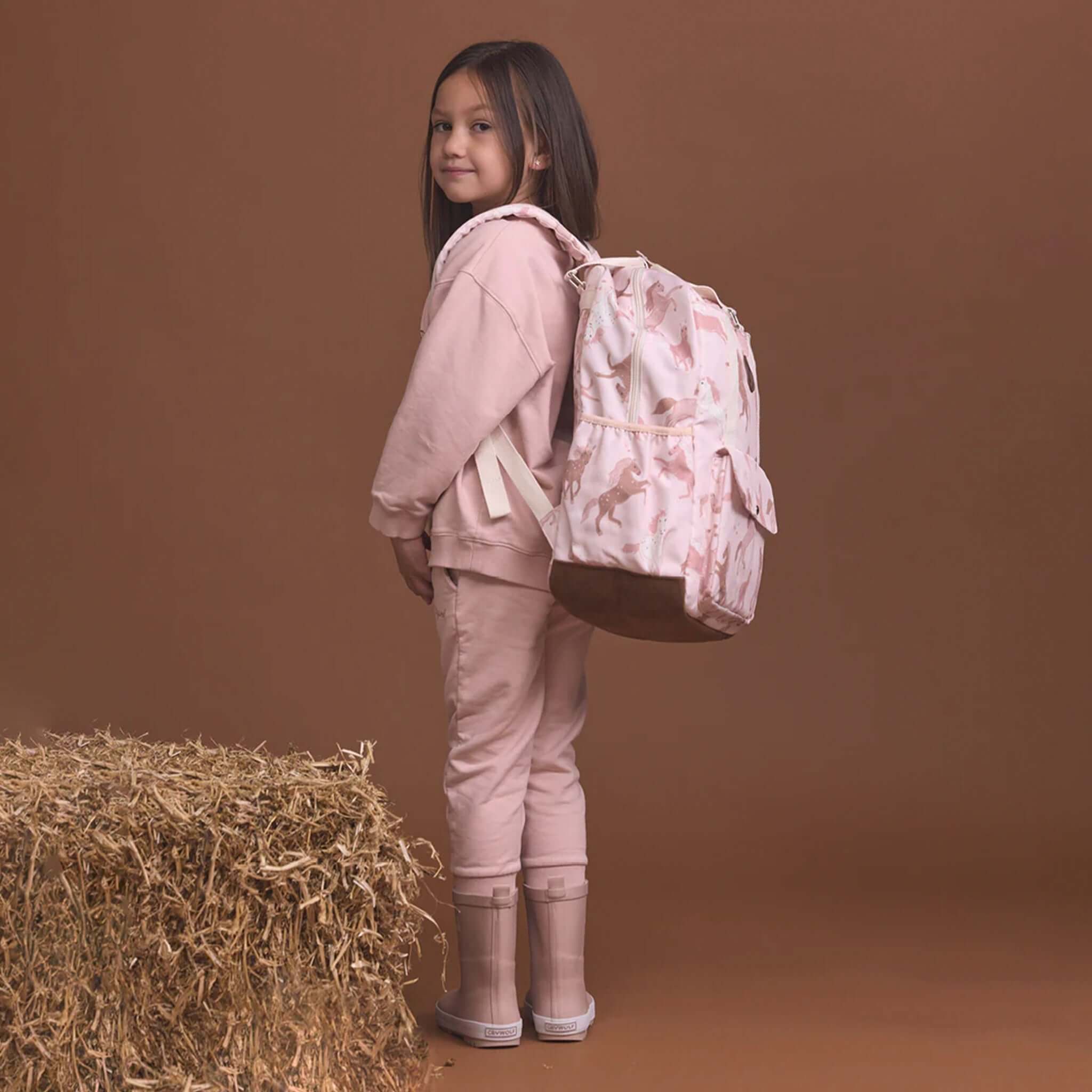 Alt Tag: Crywolf Knapsack - Blush Ponies kids water-resistant backpack in blush pony print, worn by child, recycled materials eco-friendly school bag