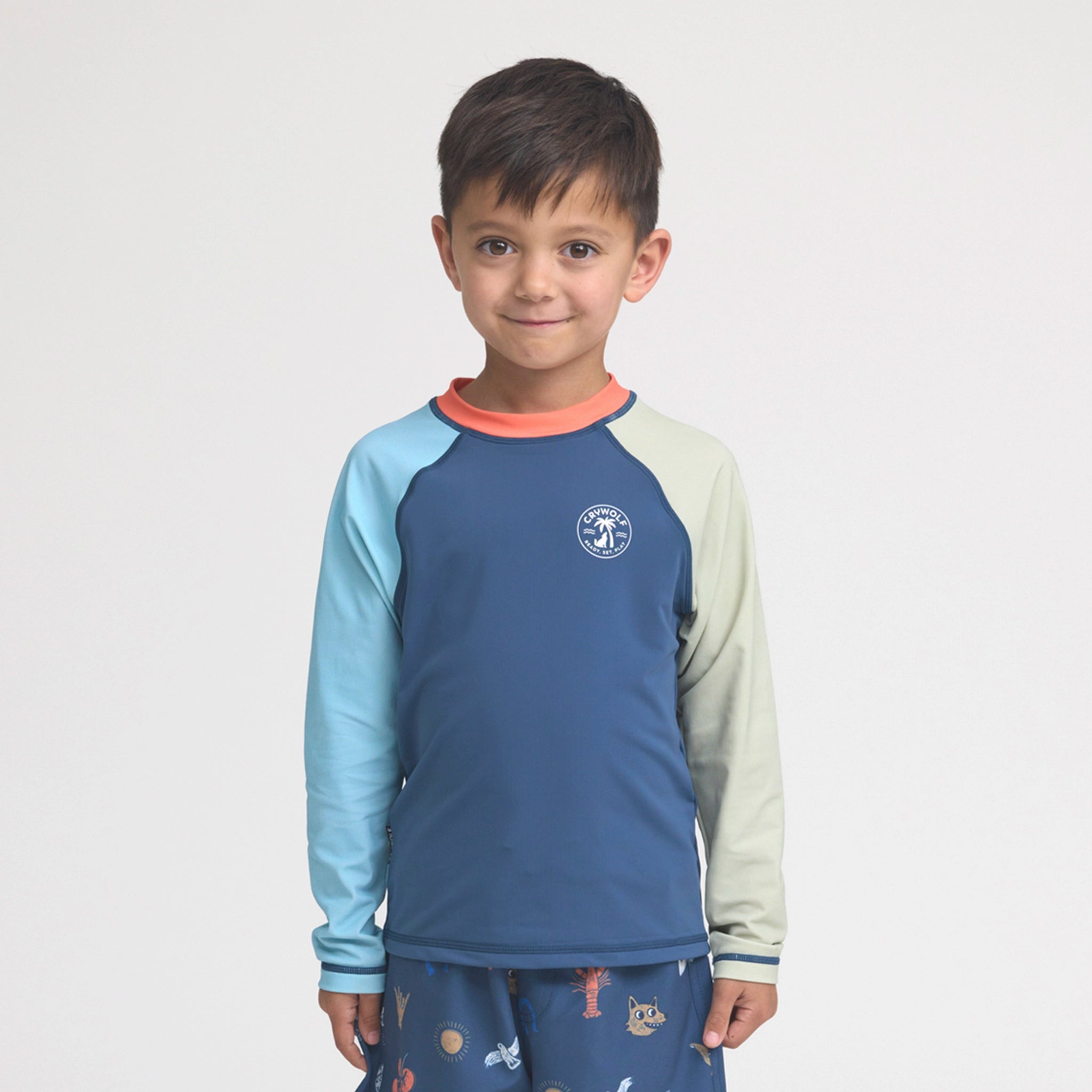Child wearing a colorful long-sleeve rash vest with a logo on a light gray background