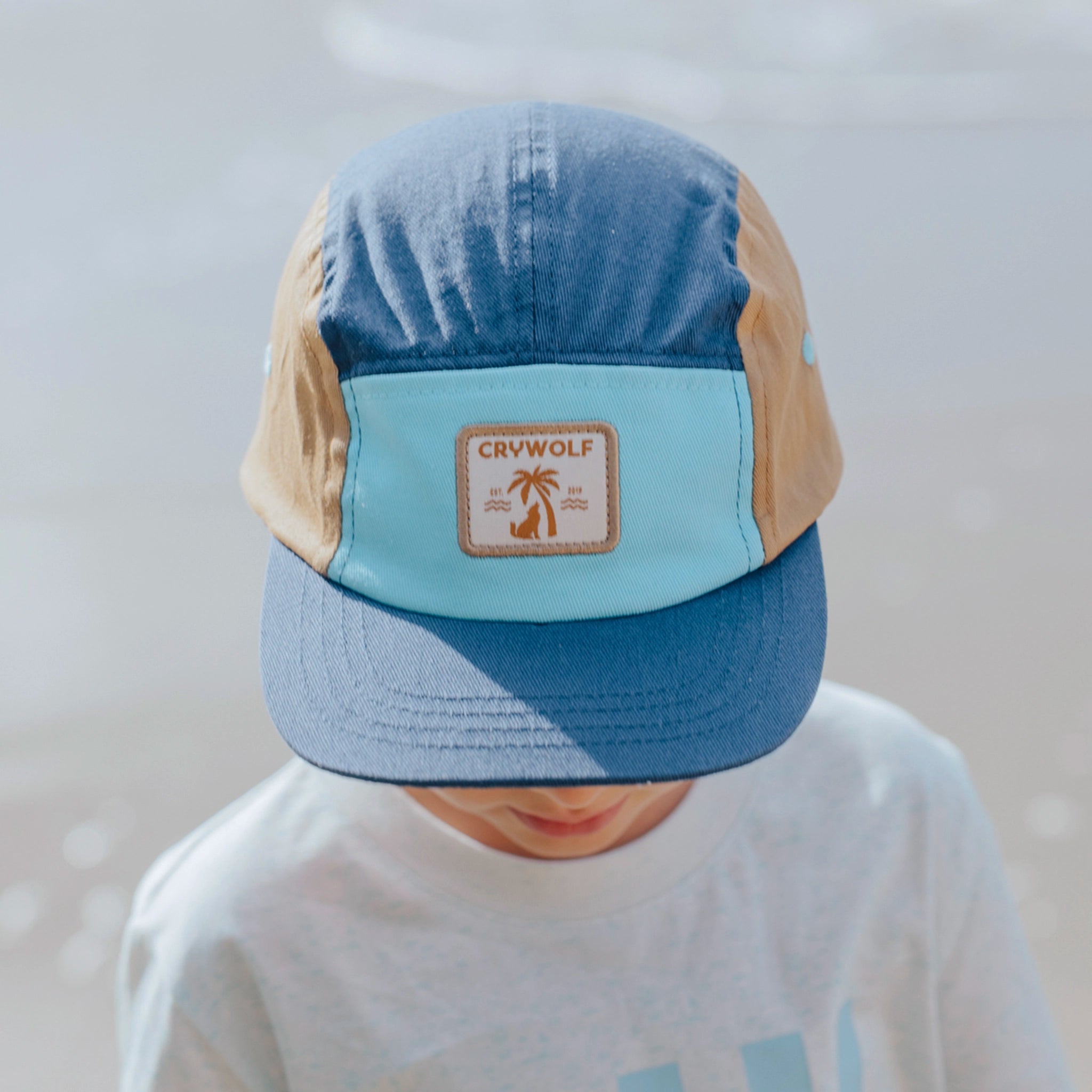 Person wearing a blue and beige cap with a visible brand logo against a blurred background