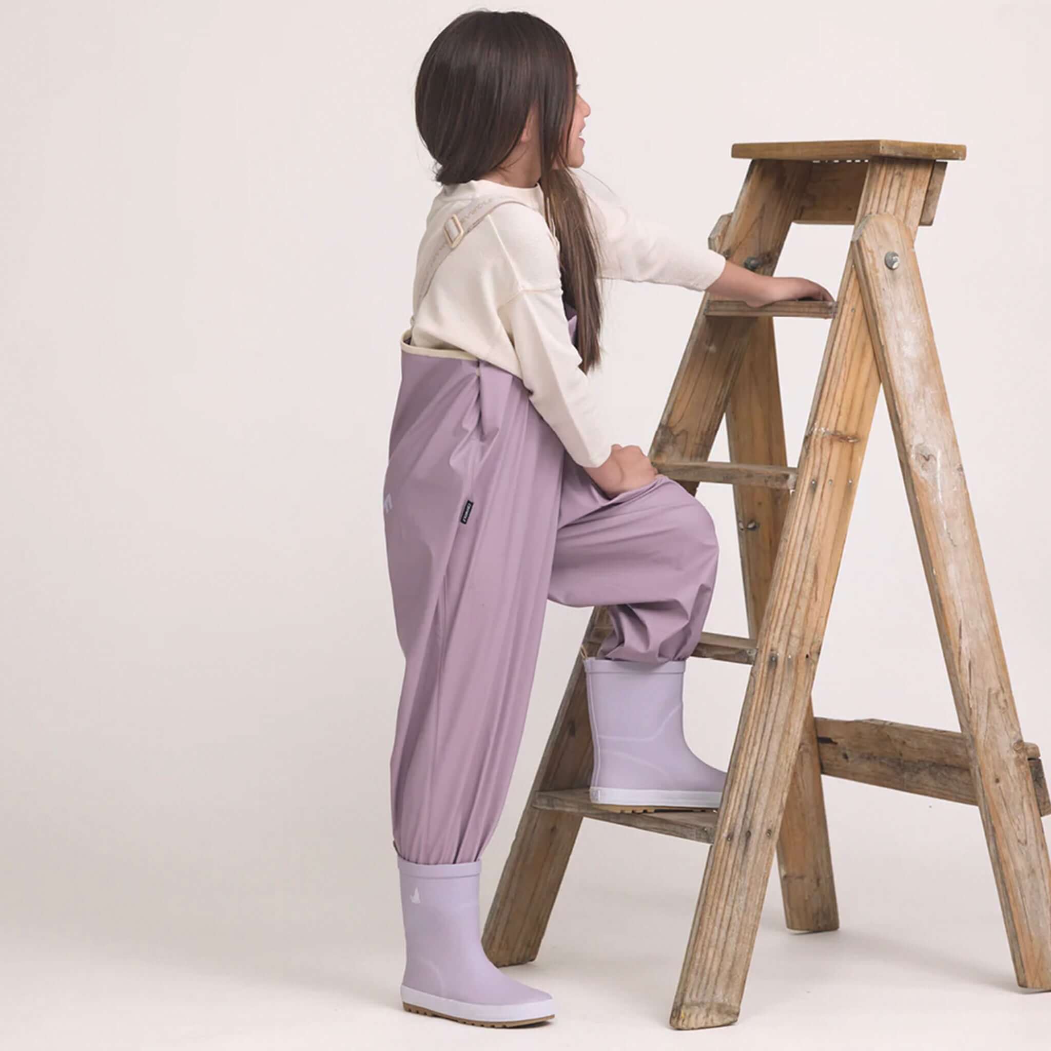 Alt Tag: Crywolf Rain Overalls - Heather waterproof kids rain overalls in heather, adjustable fit for outdoor play, model climbing wooden ladder