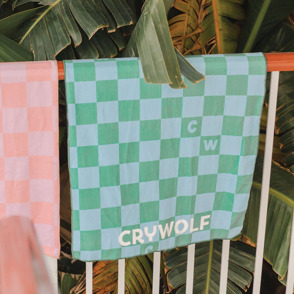 Crywolf Rapid Dry Towel - Sea Green Check hanging among tropical leaves