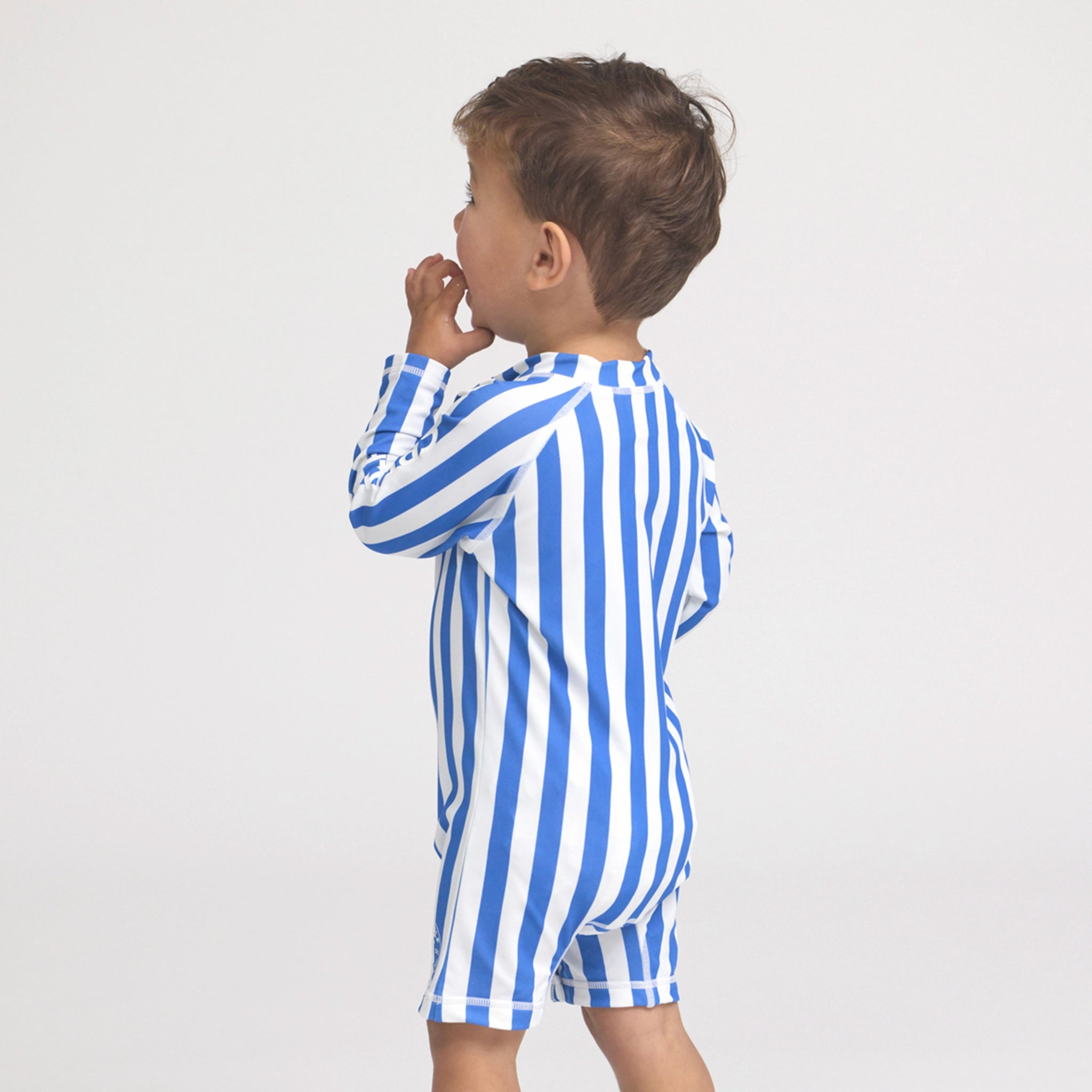 Child wearing a blue and white striped onesie on a light gray background