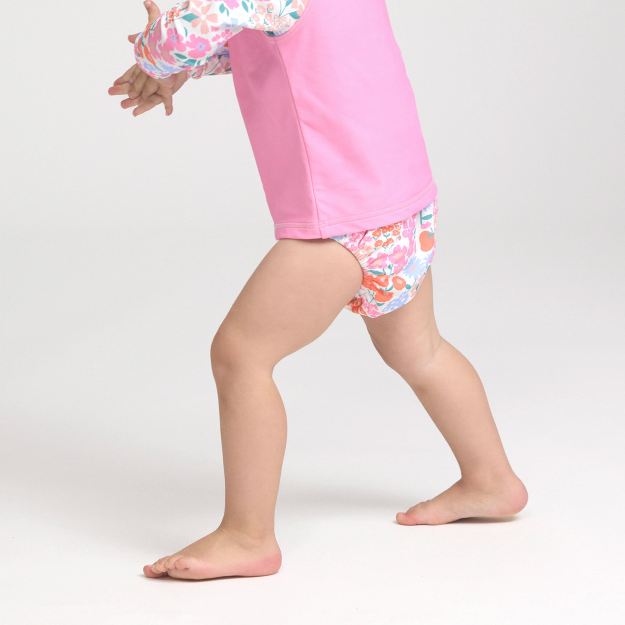 Toddler wearing a floral swim nappy on a white background