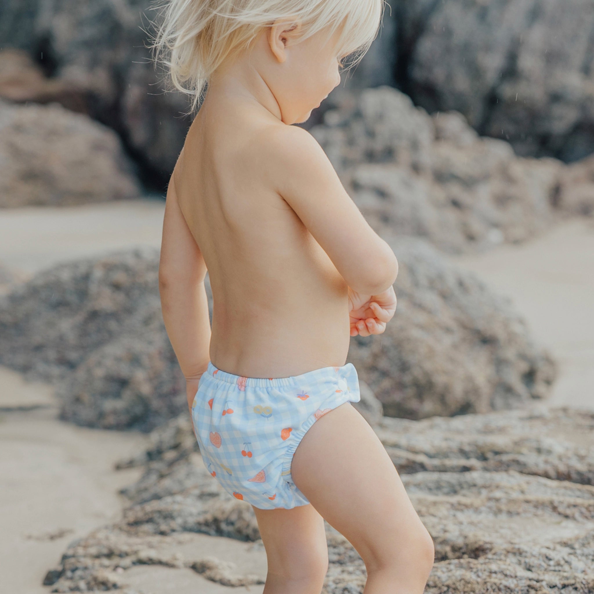 Toddler wearing a  blue and pink checkered swim nappy at the beach