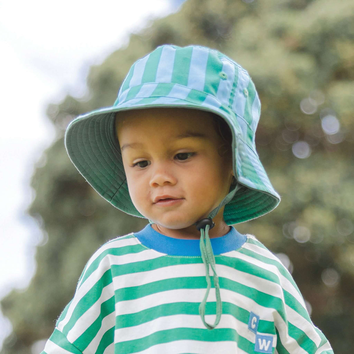 Child wearing a Crywolf Reversible Bucket Hat - Deck Stripe outdoors on a sunny day.