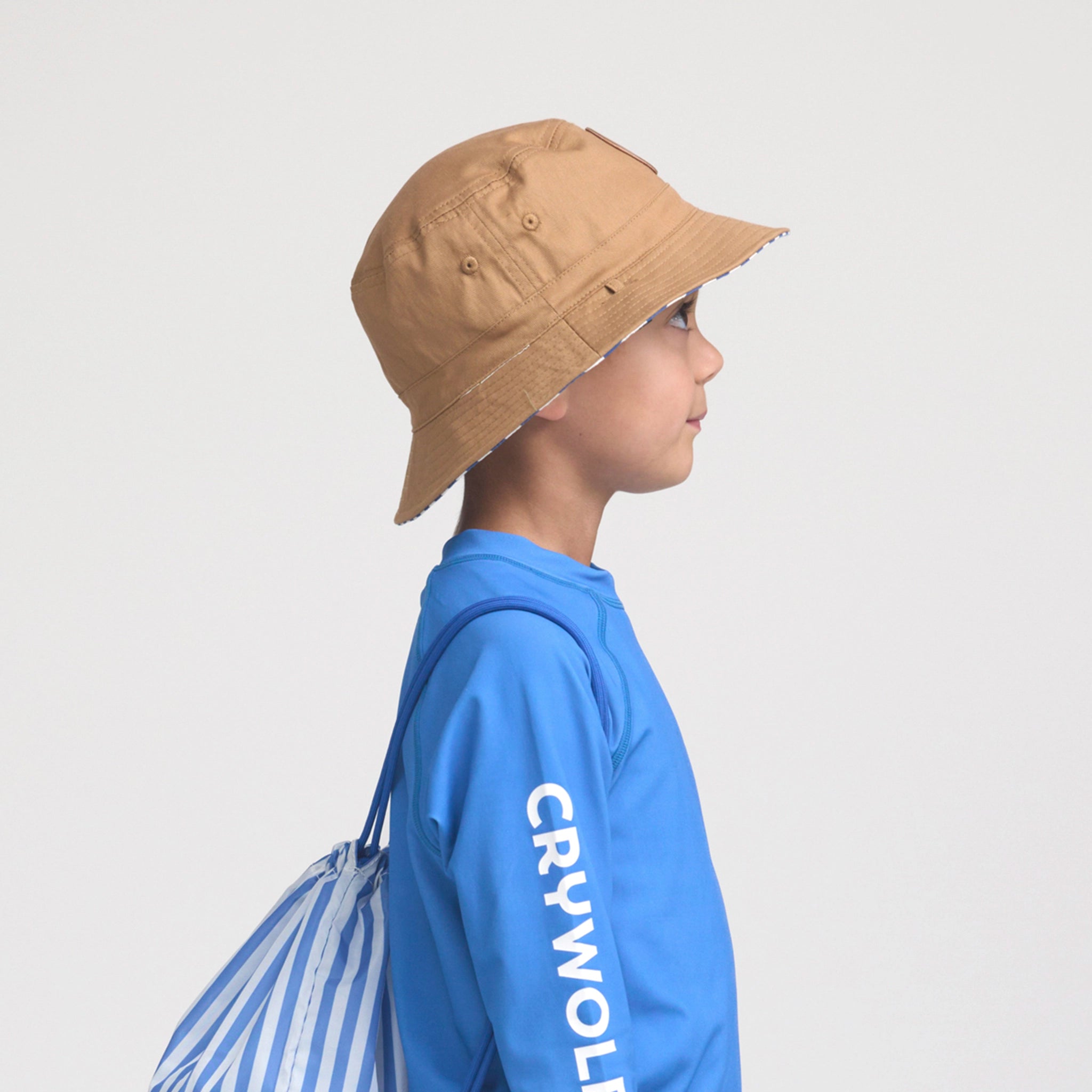 Person wearing a tan bucket hat and blue hoodie with 'CRYWOLF' branding, standing against a light gray background.