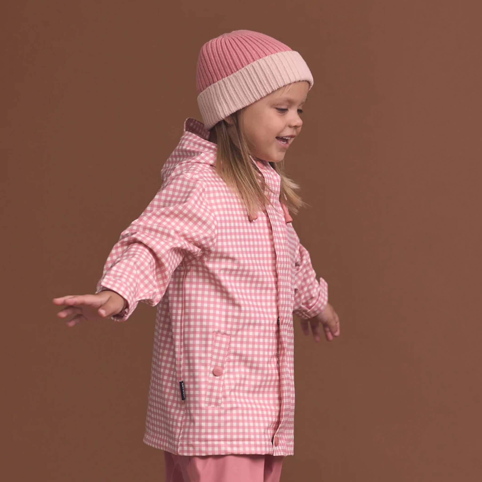 Crywolf Tasman Beanie - Rose worn by child, slimline ribbed knit pink beanie under hood-ready fit for active kids