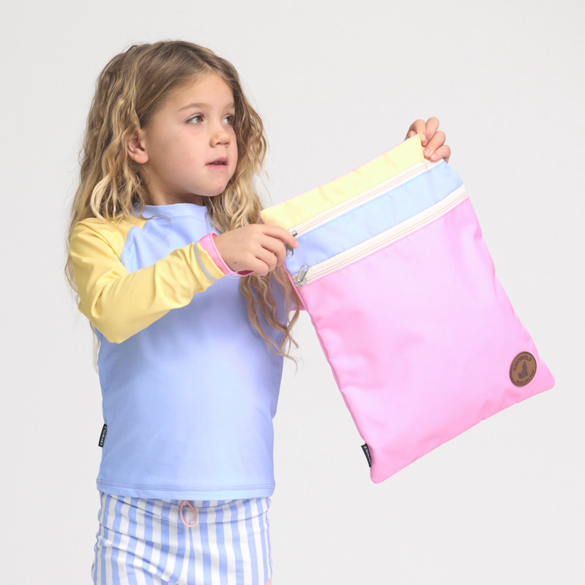 Girl holding a multicolored swim bag.