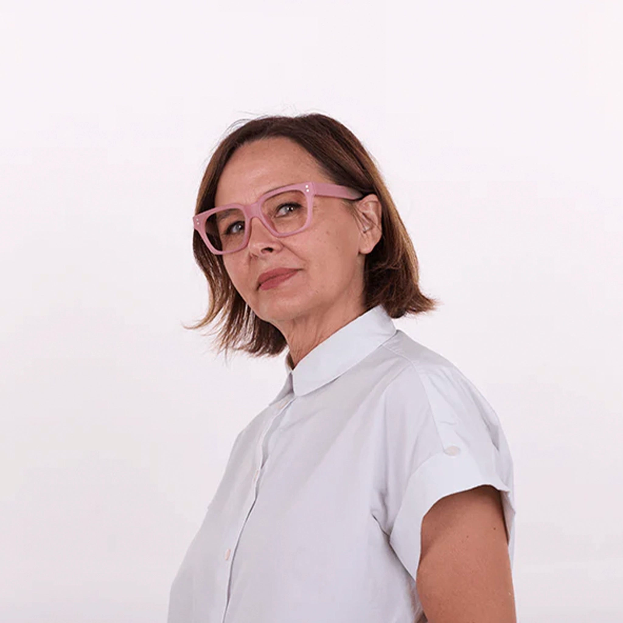 Woman wearing a white shirt and pink glasses on a white background