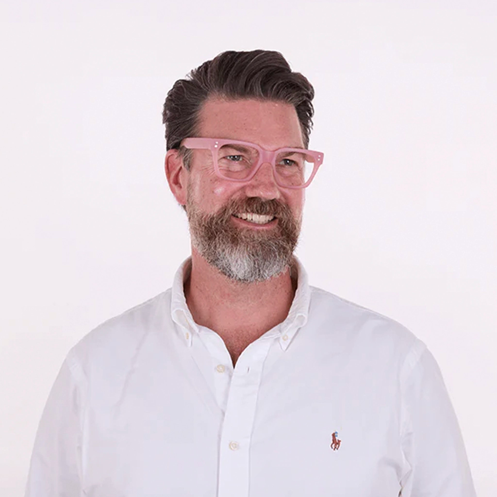 Man wearing pink glasses and a white shirt with a logo on a white background