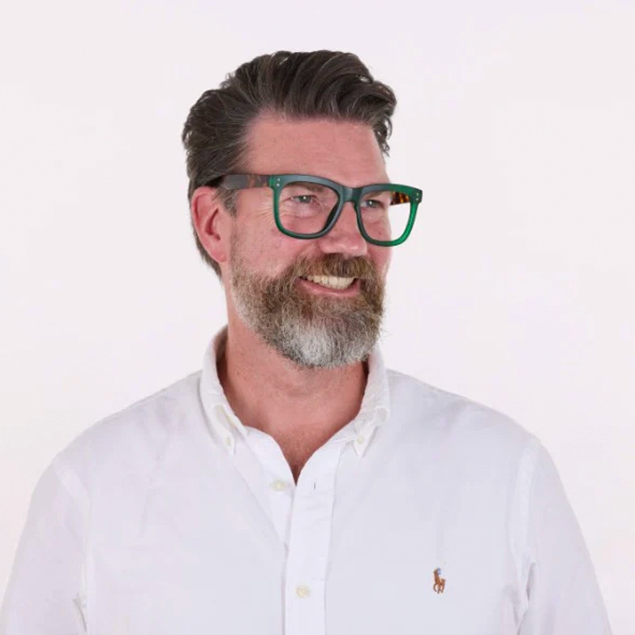 Man wearing green glasses and a white shirt with a logo on a white background