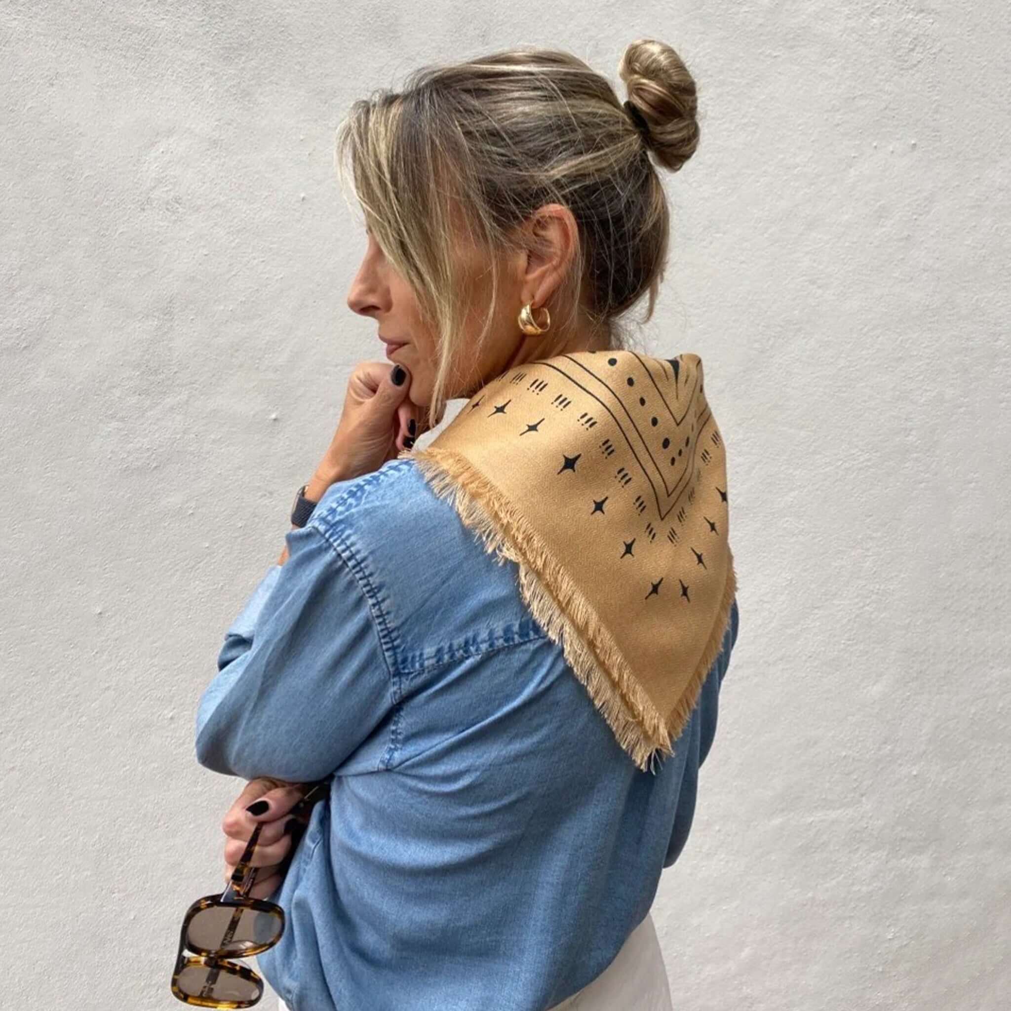 Woman wearing Dark Hampton x Ellie Compton The Holden Wool Silk Scarf in tan with intricate design.