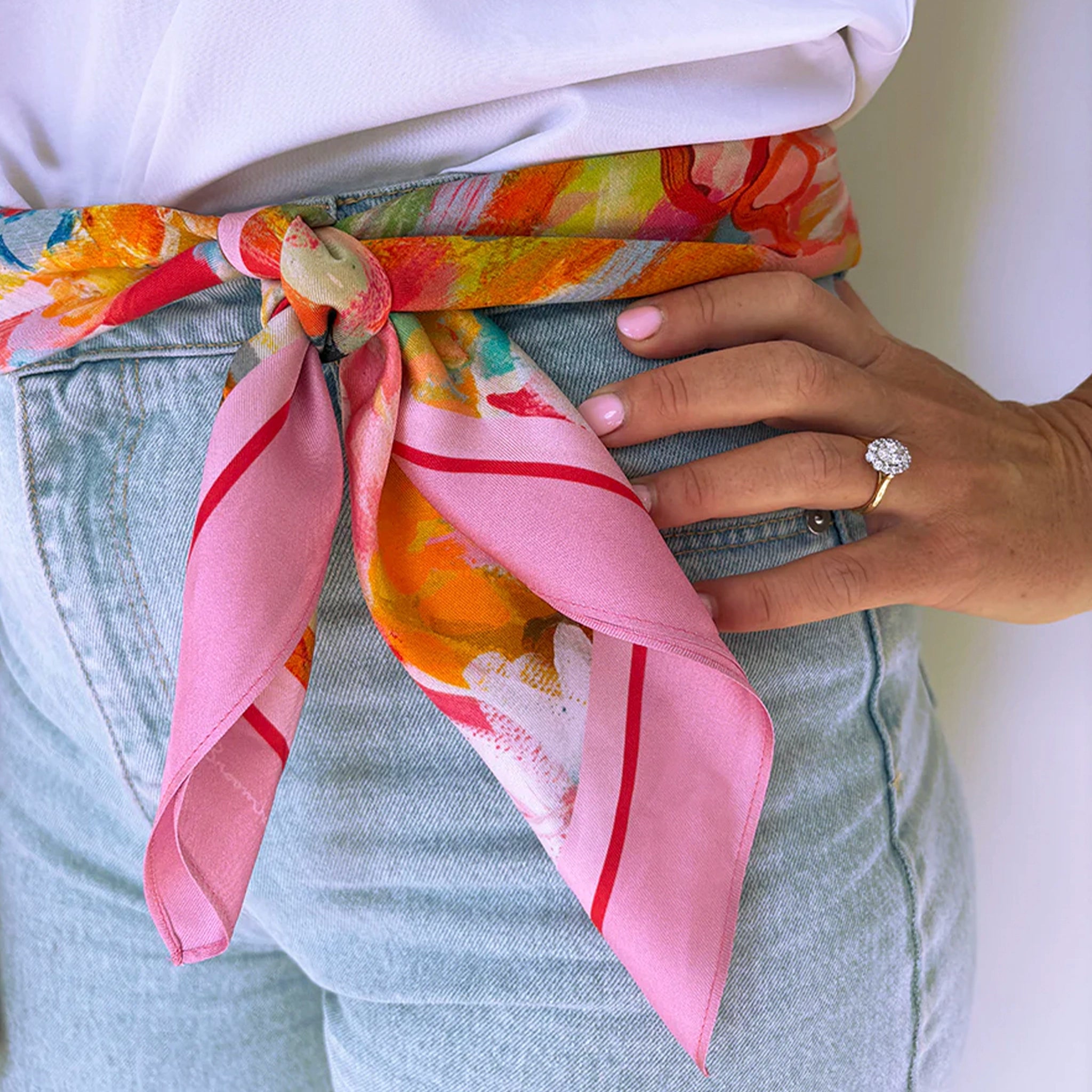 Person wearing a colorful scarf with pink accents around their waist, holding a phone.