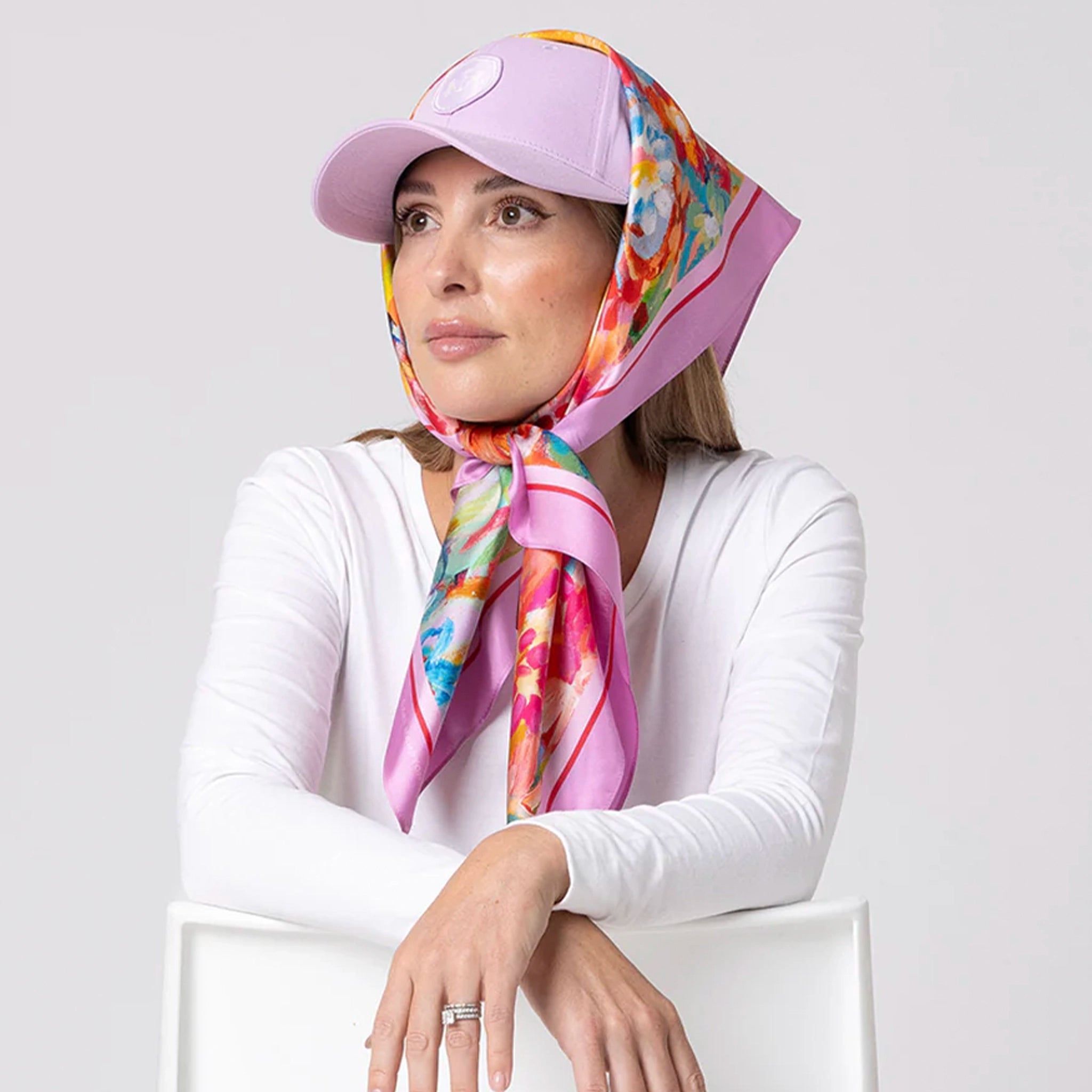 Woman wearing a colorful headscarf and pink cap on a white background