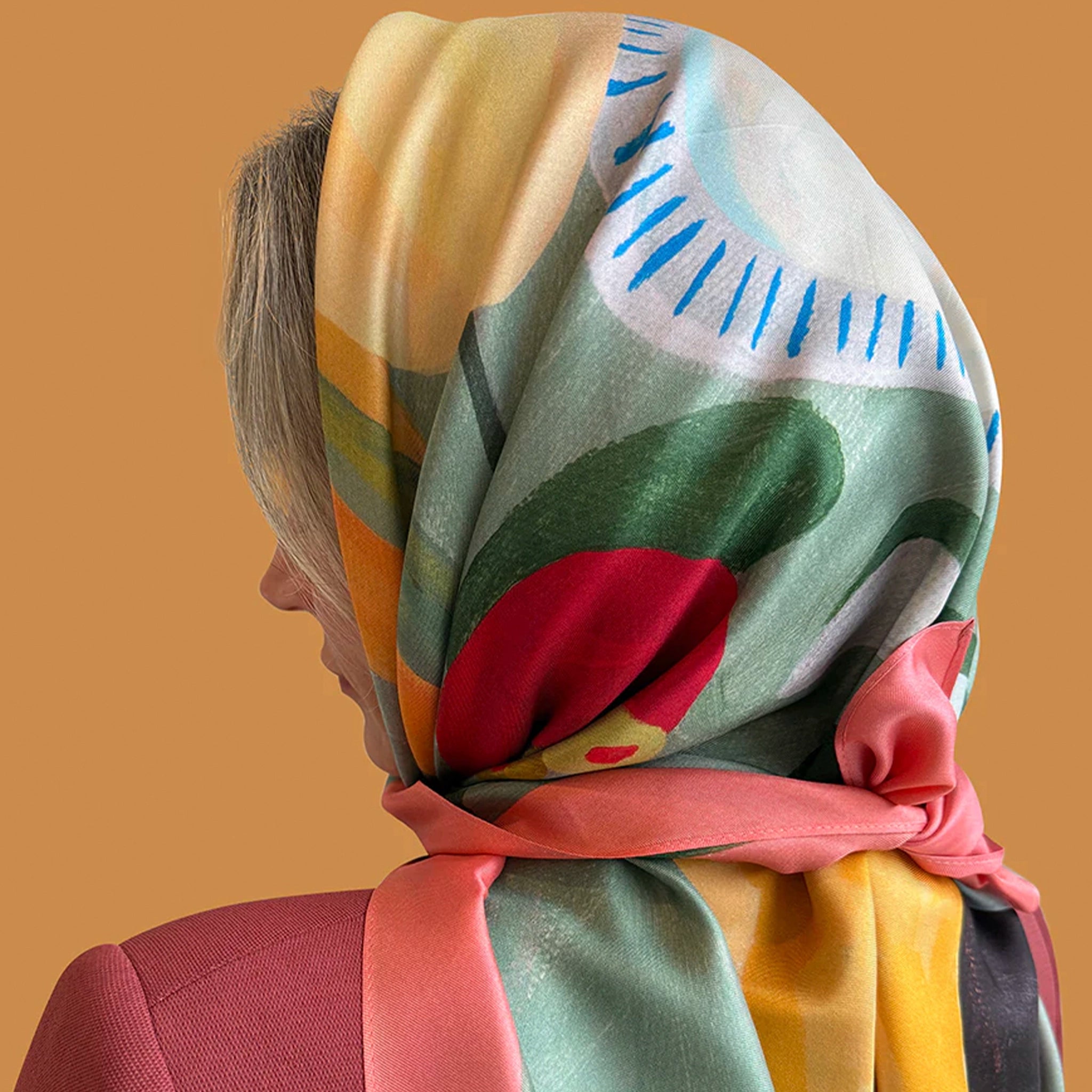 Person wearing a colorful headscarf with abstract patterns on a beige background